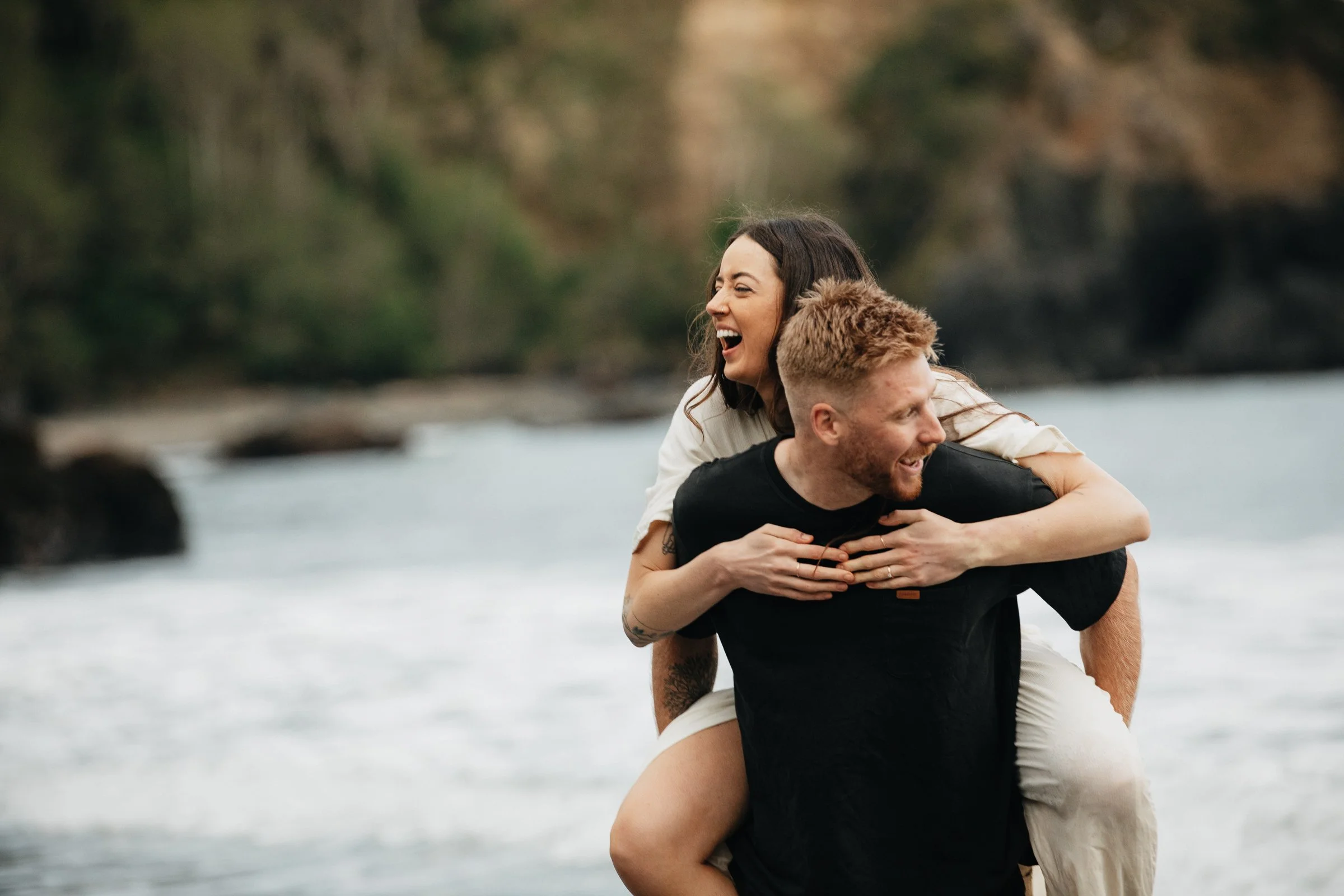 Beach engagement photos on the Oregon Coast featuring an adventurous couple surrounded by wind, waves, and rugged shoreline.