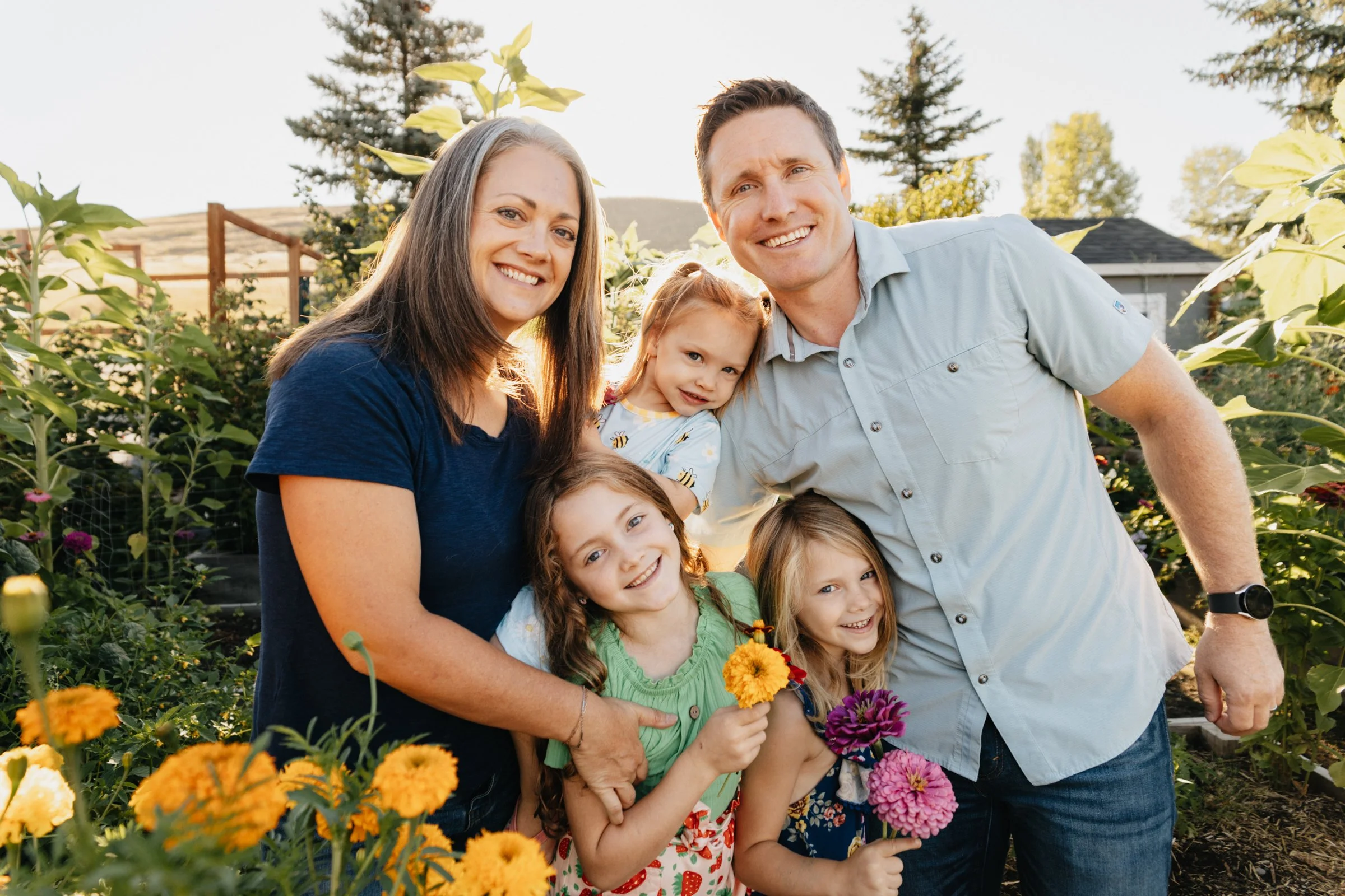 Missoula family photographer capturing a summer garden session with parents and kids surrounded by vegetables, flowers, and natural light in Montana.