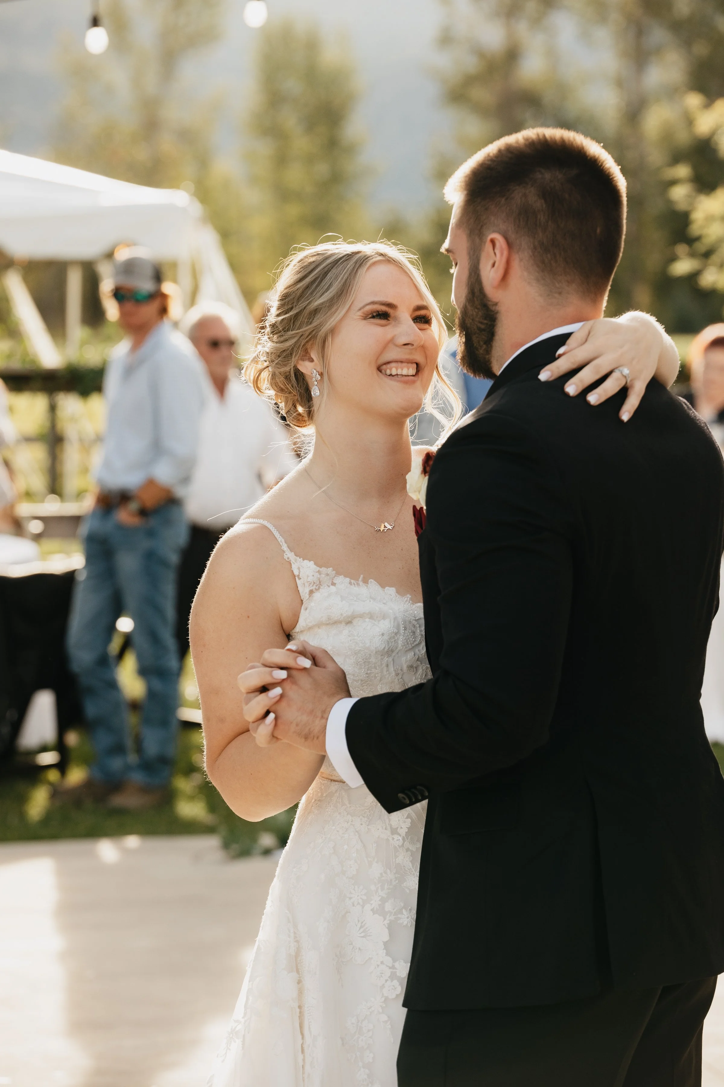 Missoula wedding photographer capturing a bride and groom’s first dance at an outdoor Montana wedding reception, surrounded by smiling guests.