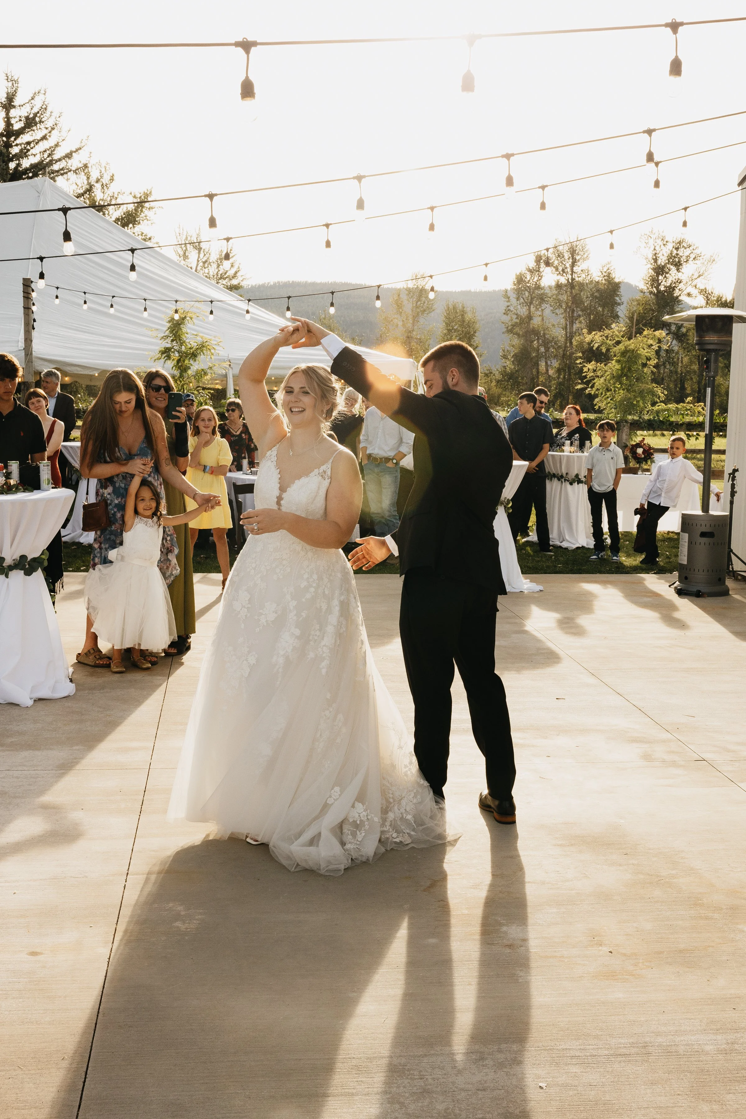 Missoula and Montana wedding photographer capturing a bride and groom dancing at their outdoor wedding reception, with guests watching in the background.