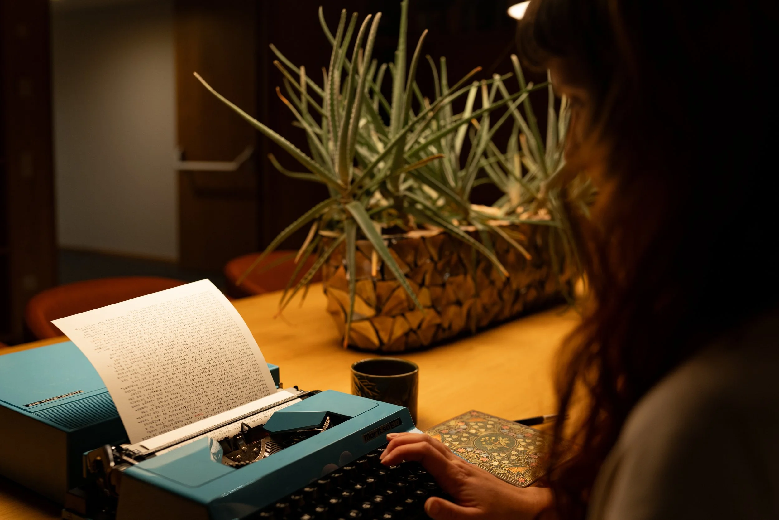 Travel writer Lucy working on a typewriter in low light, writing longform travel essays and documentary storytelling from life on the road