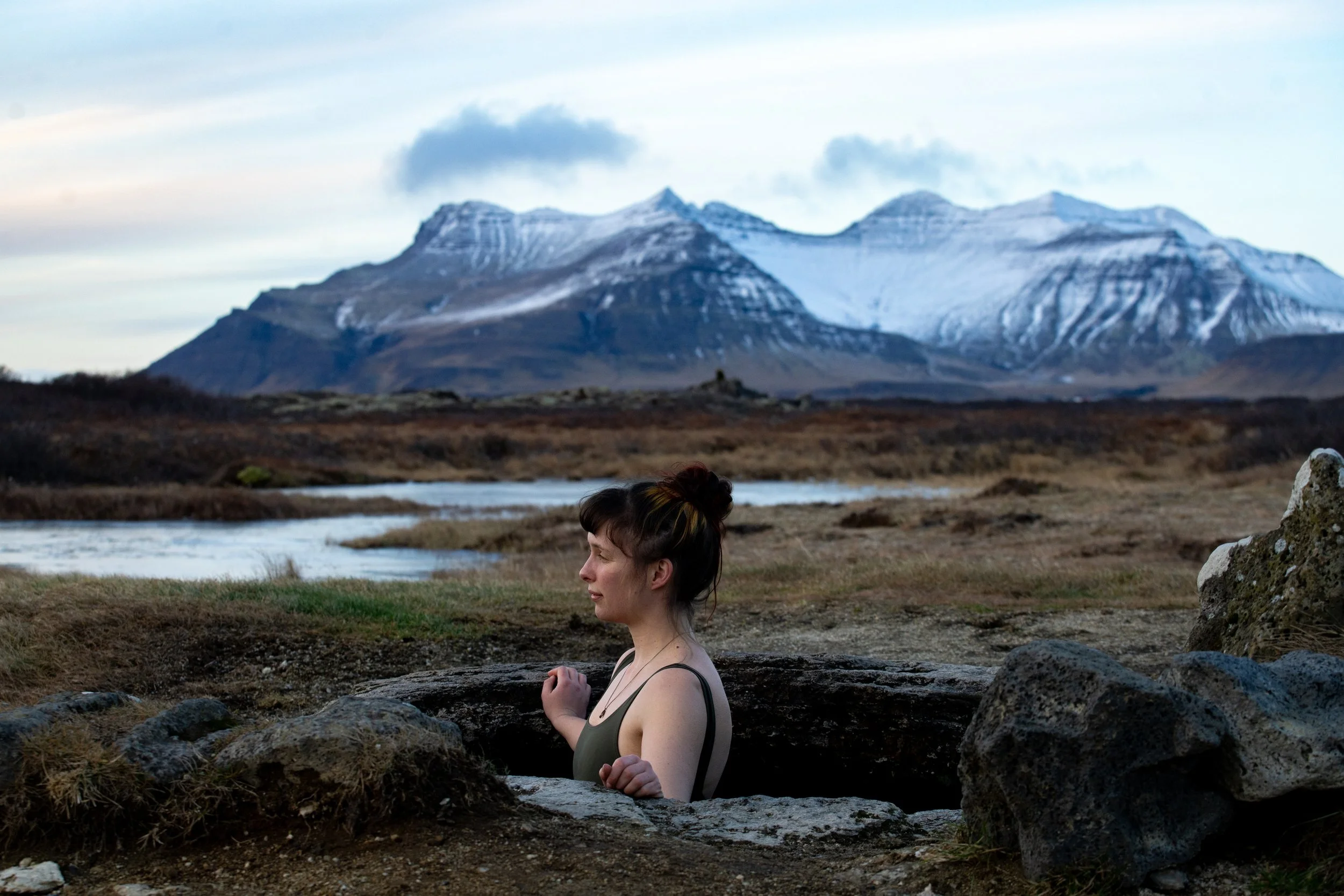 Cinematic film still of Lucy bathing in a natural hot spring during an expedition-based documentary exploring geothermal landscapes