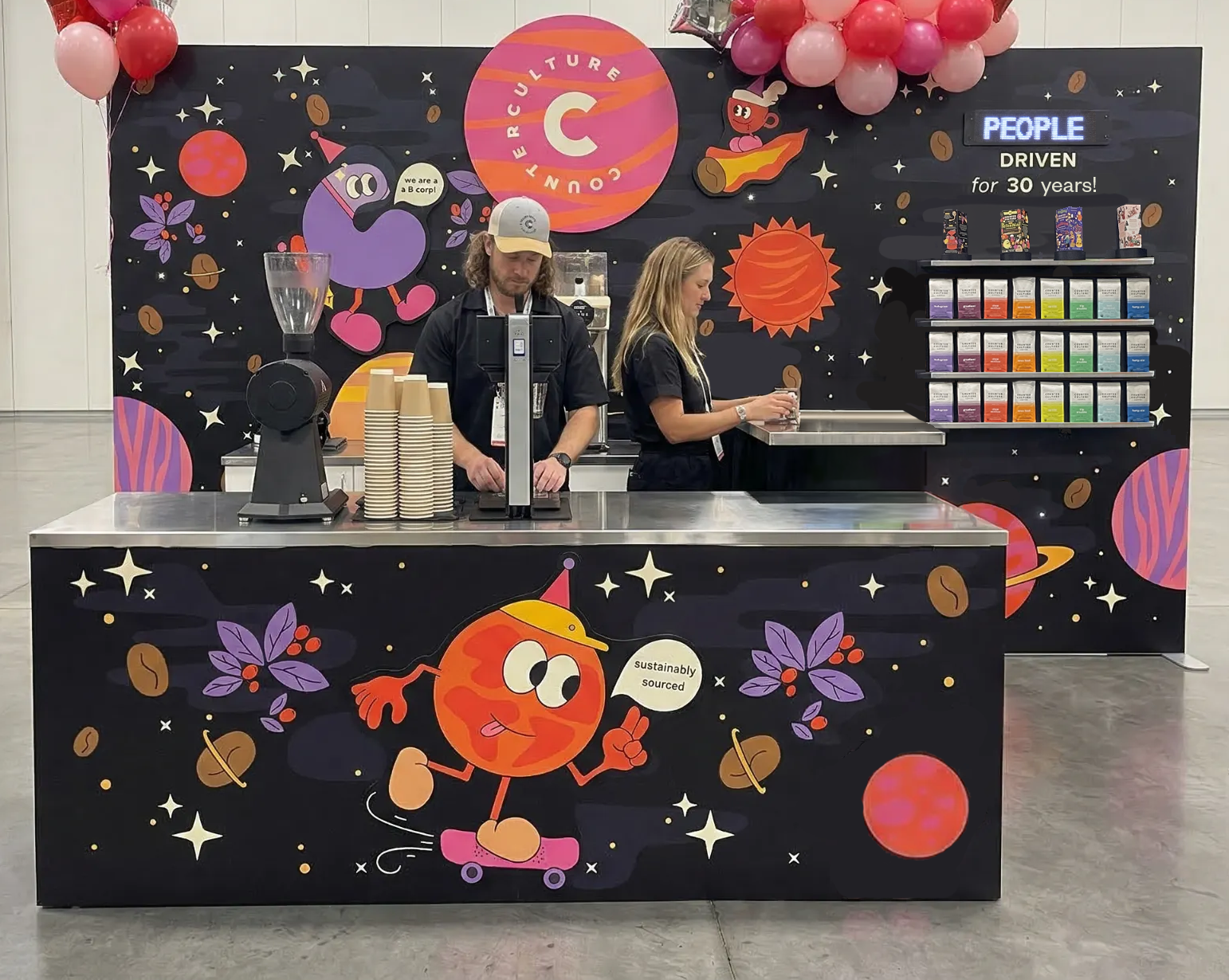 Counter Culture Coffee Expo West 2025 trade show booth — 30th anniversary space theme with illustrated planets, characters, and coffee bar backdrop
