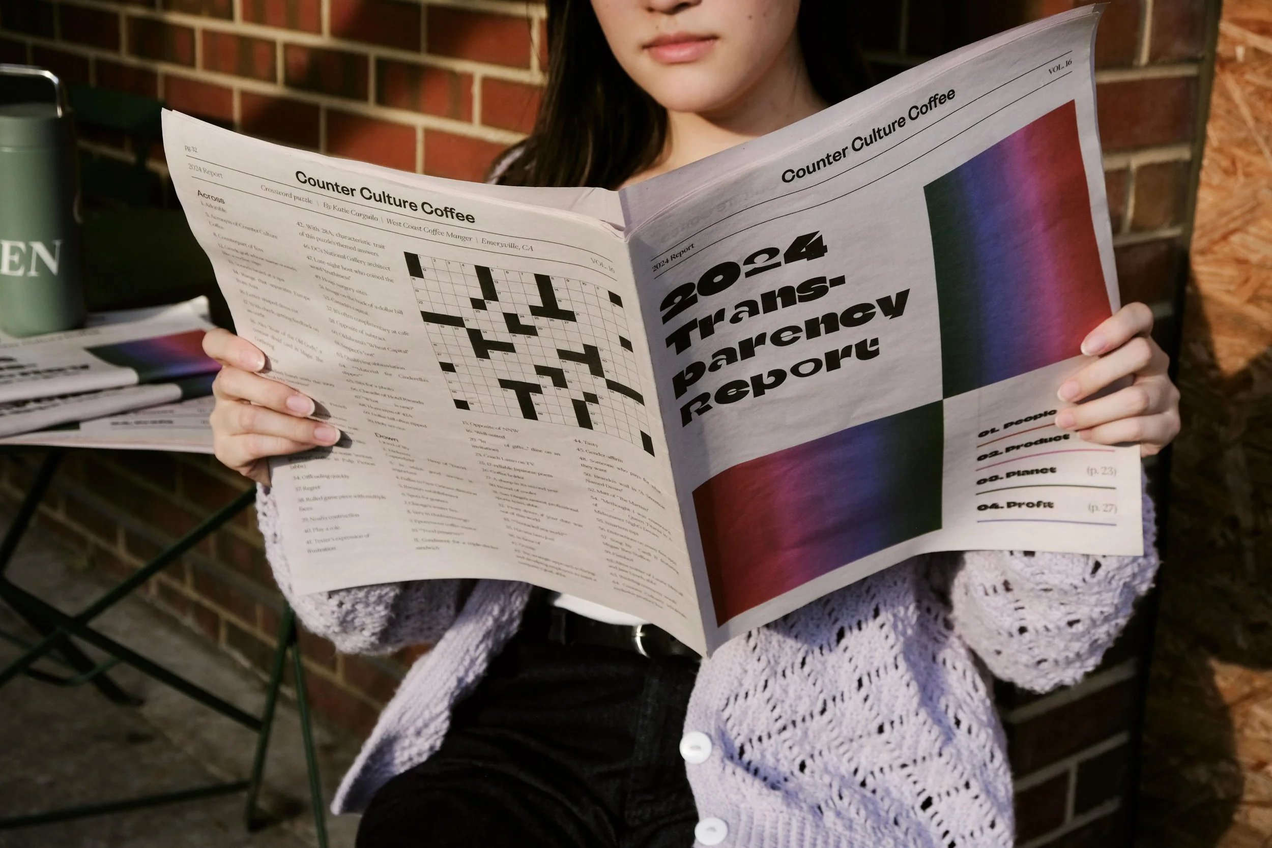 Counter Culture Coffee 2024 Transparency Report printed newspaper — person reading broadsheet newspaper version outdoors