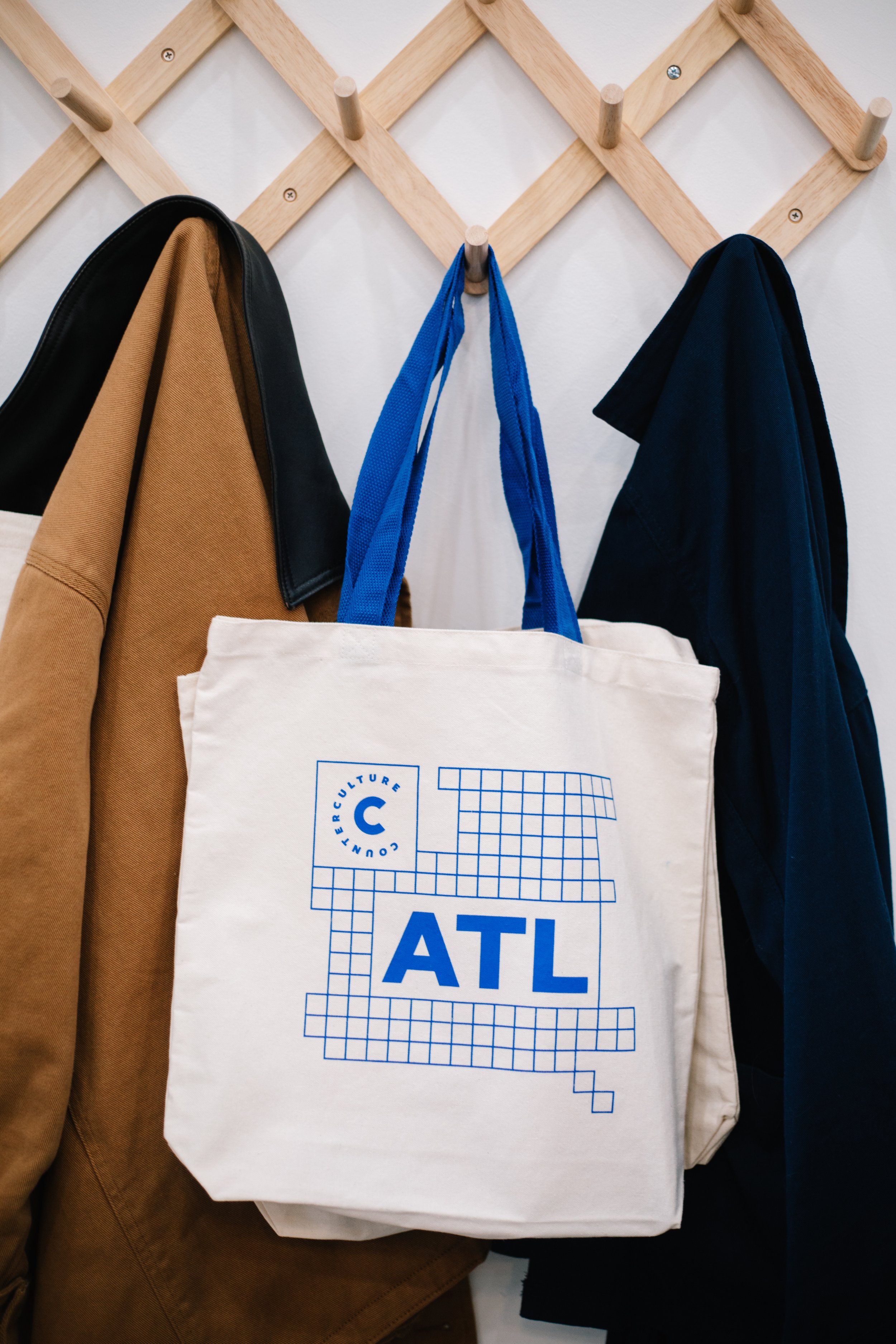 Counter Culture Coffee Atlanta ATL branded tote bag — white canvas bag with blue grid graphic and ATL typography hanging on wooden rack
