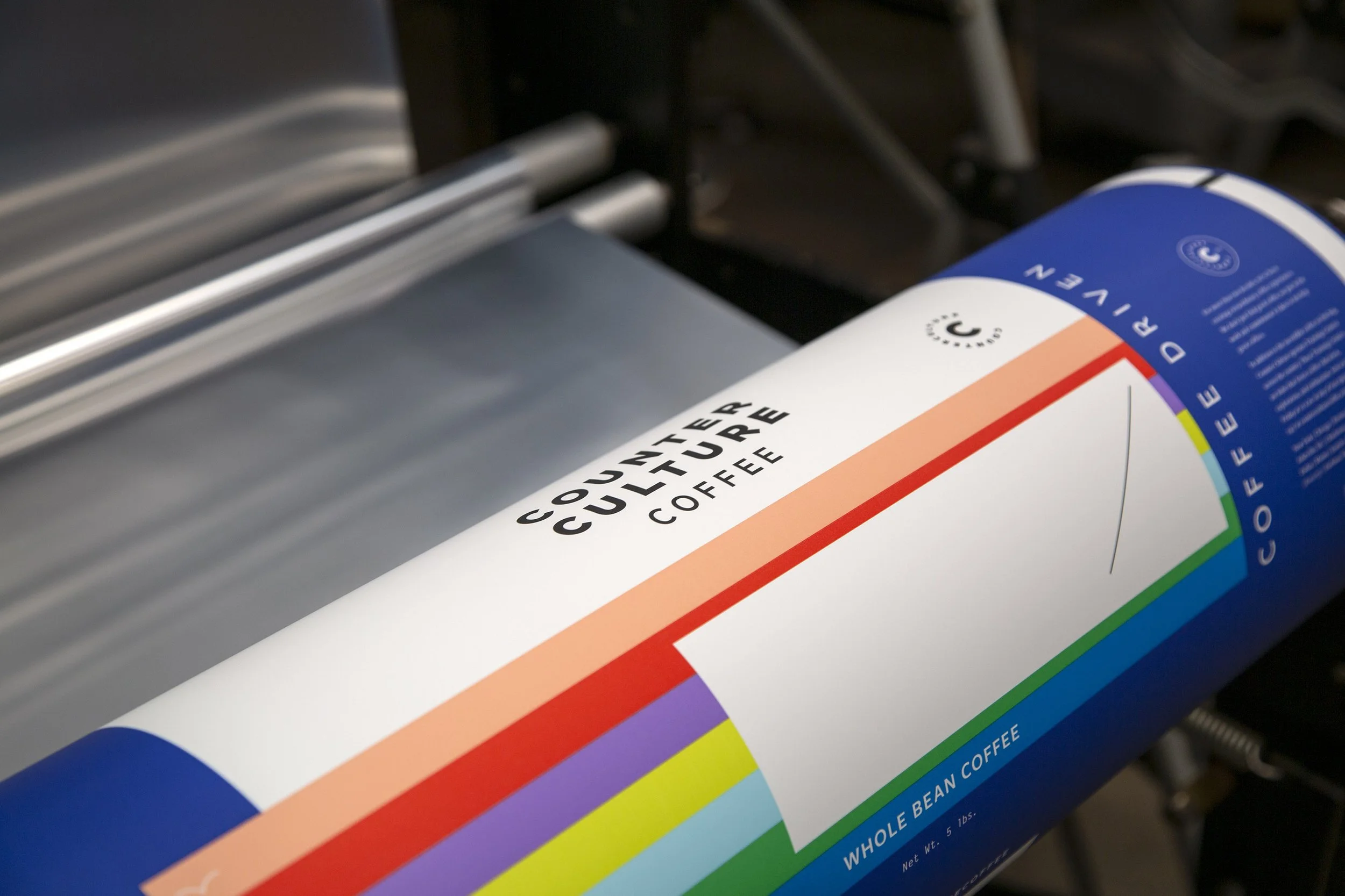 Counter Culture Coffee bulk packaging detail — multicolor horizontal stripe 1.5lb whole bean coffee bag on roller