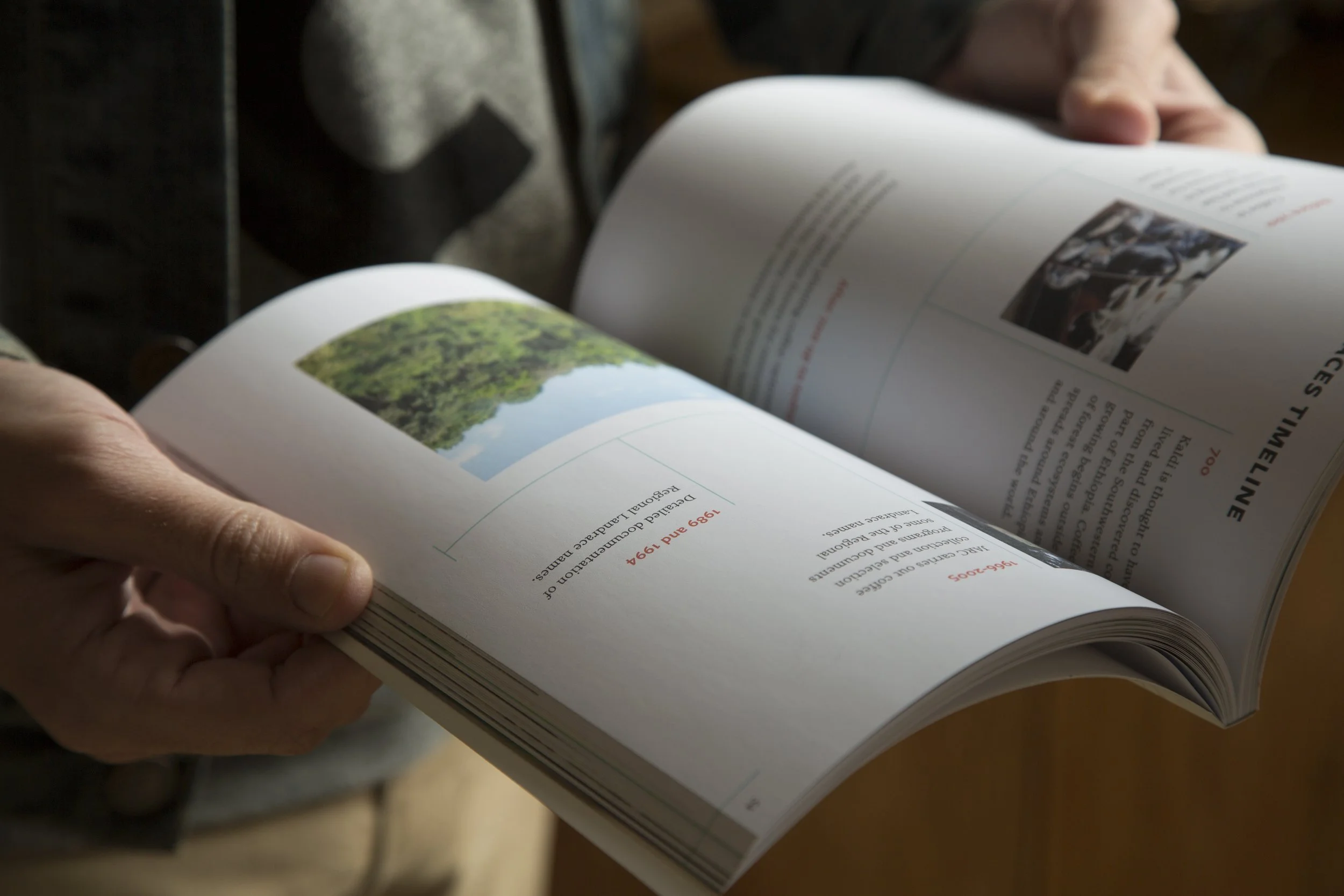 A Reference Guide to Ethiopian Coffee Varieties interior — hand holding open book showing text layout and coffee farm photography