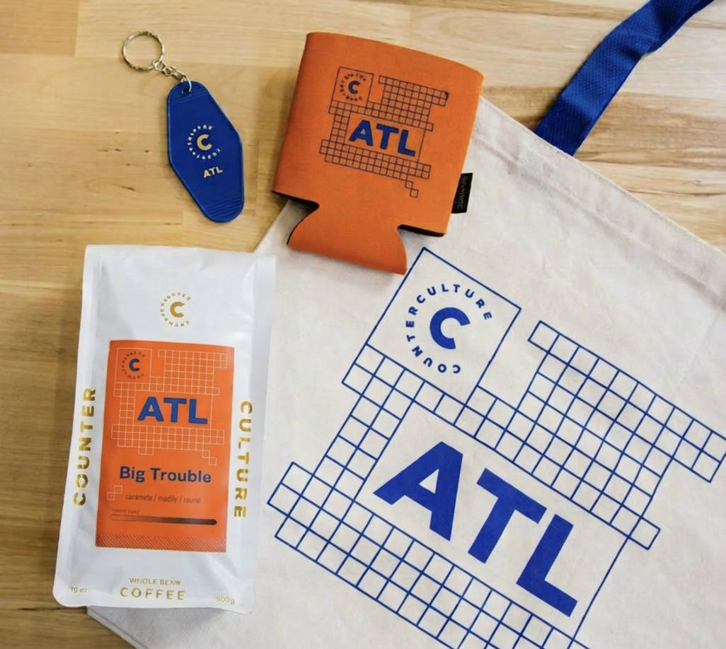Counter Culture Coffee Atlanta ATL merchandise — branded tote bag, koozie, keychain and coffee bag flatlay