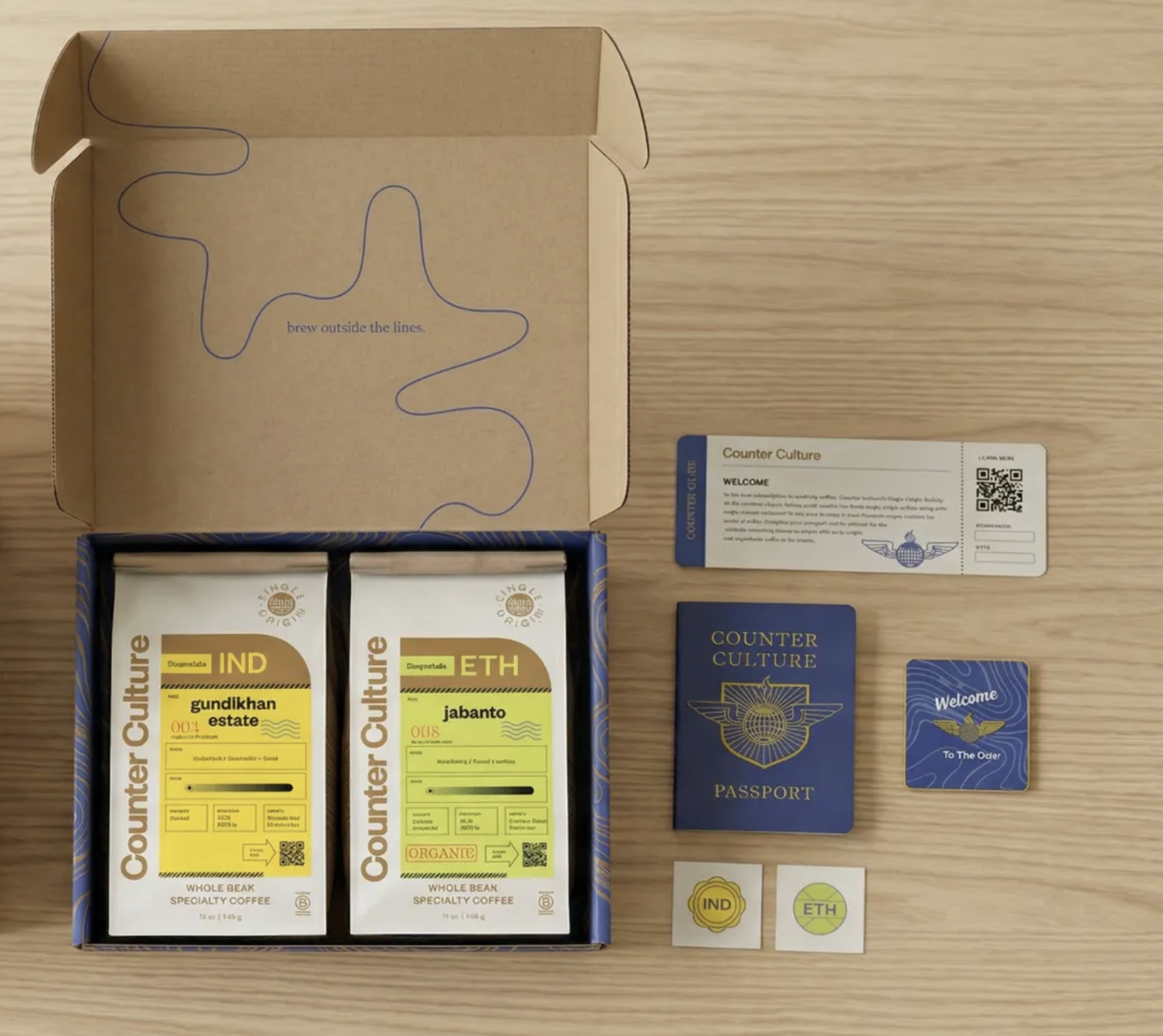 Counter Culture Coffee Club concept proposed packaging — kraft box with passport booklet, destination coffee bags, welcome card and enamel pins flatlay