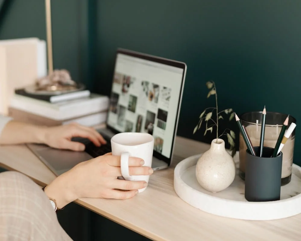 laptop and hand holding a cup