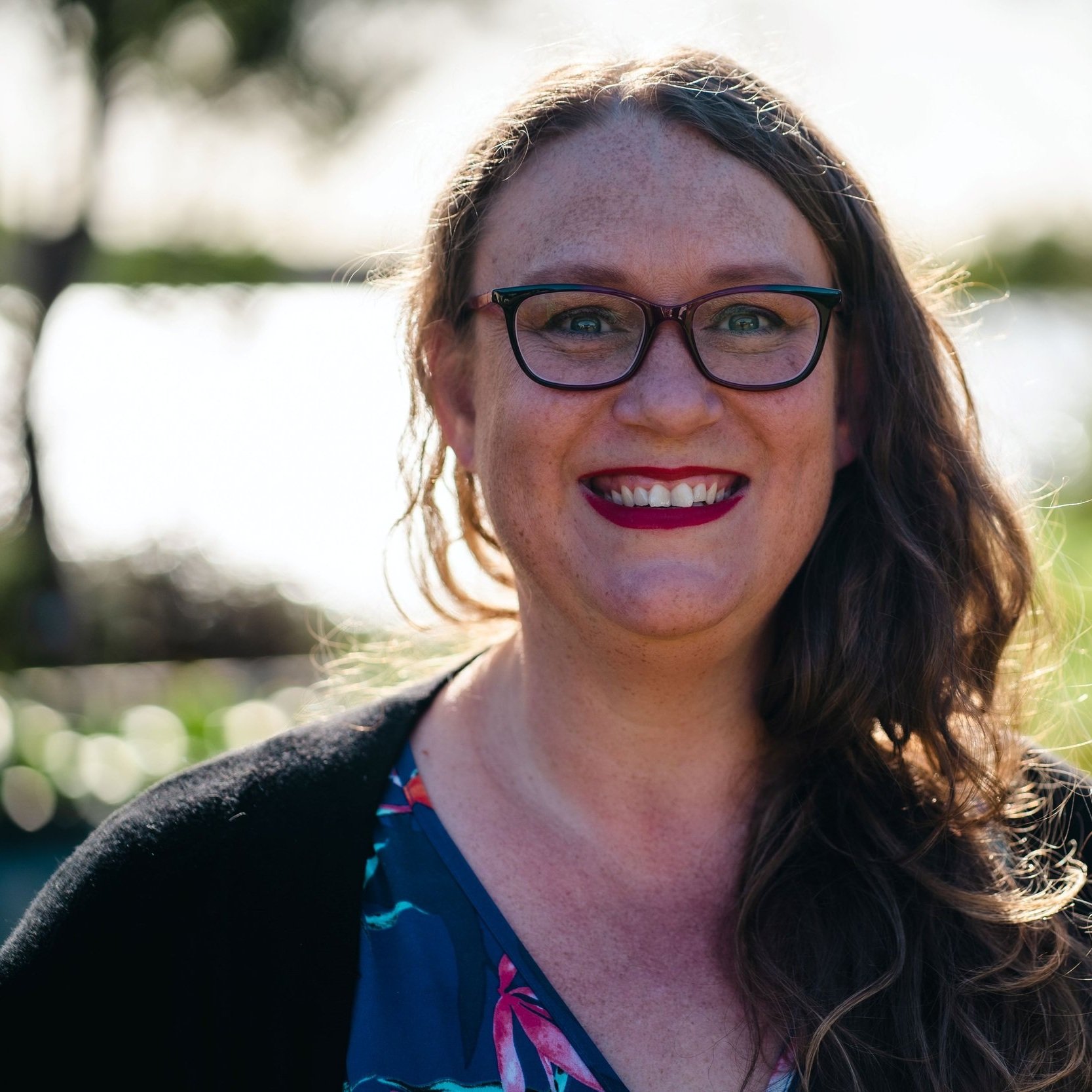 Christie+Lange_picture+of+the+artist+who+has+long+hair+in+a+side+pony+tail+glasses+and+a+big+smile+standing+in+front+of+Grants+Lagoon+in+Binalong+bay.jpg