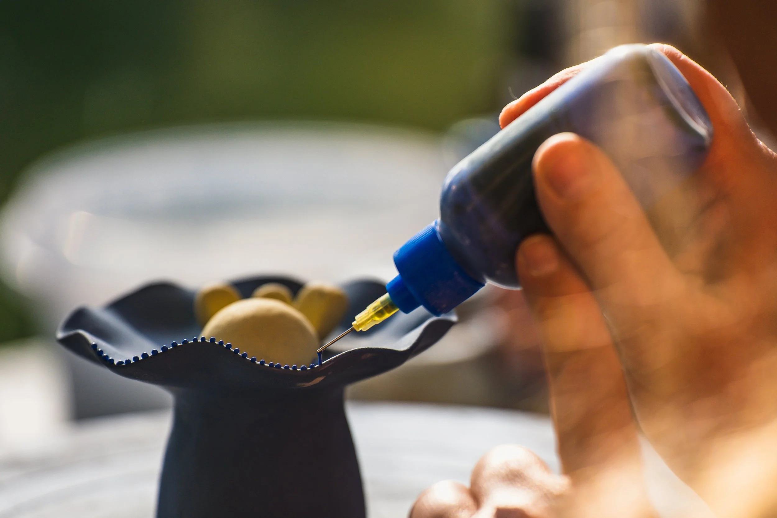 Christie Lange: Artists hand applying liquid clay slip dots to sculpture