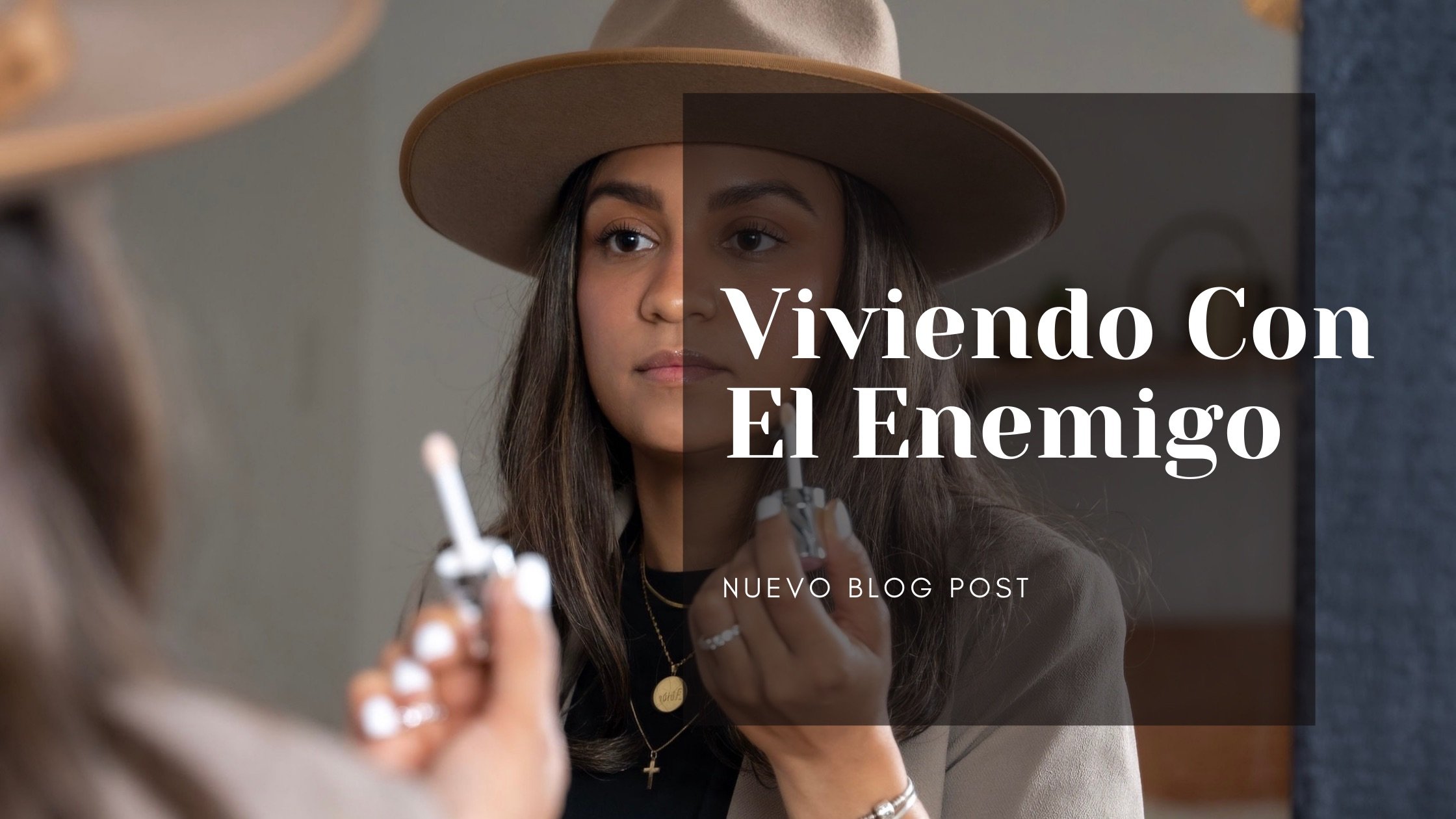 A woman with long hair wearing a hat looks into a reflective mirror, holding a lipstick. Overlaid text reads 'Viviendo Con El Enemigo' and 'Nuevo Blog Post.'