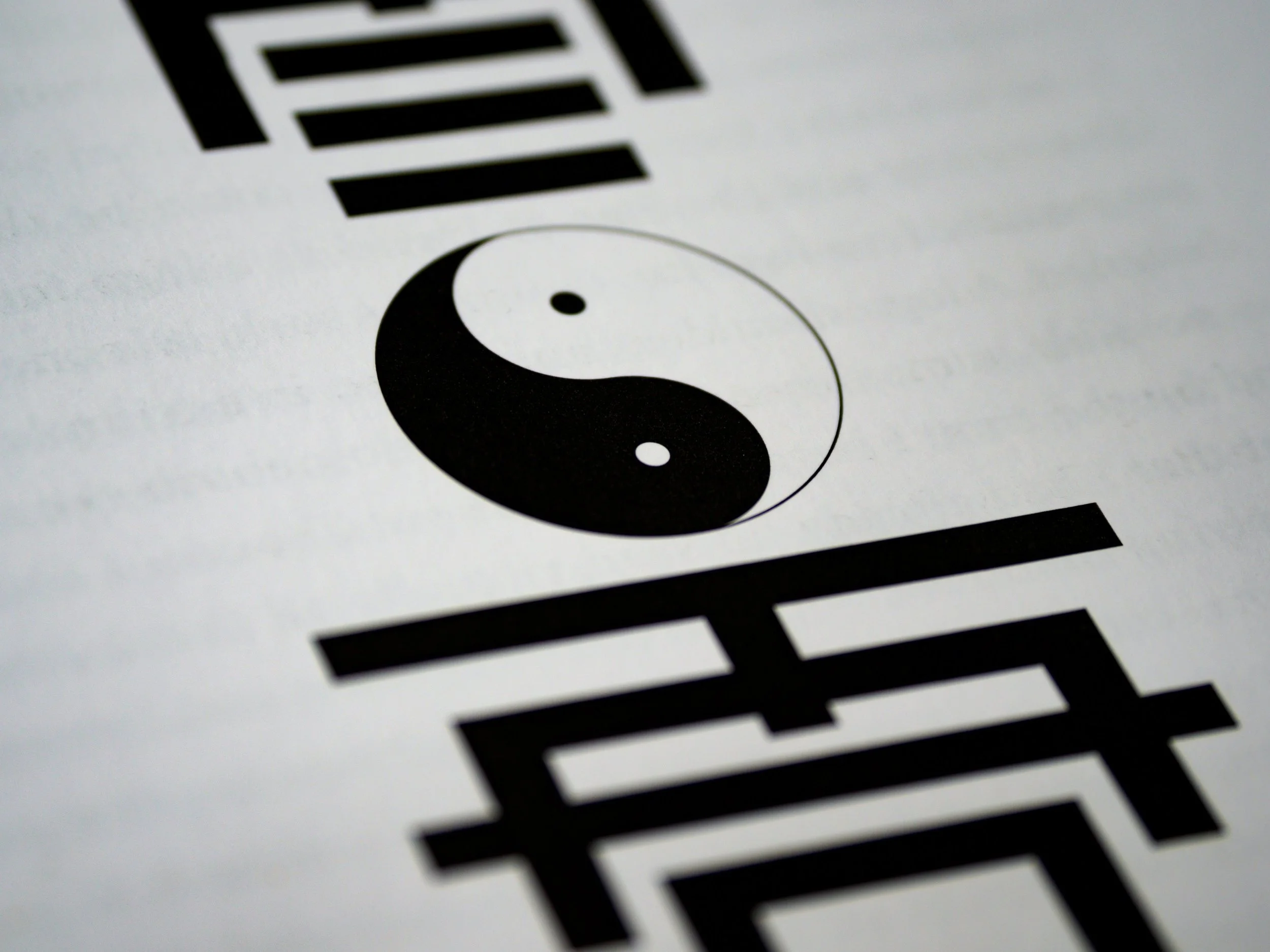 Yin-yang symbol surrounded by black and white horizontal lines on white paper.