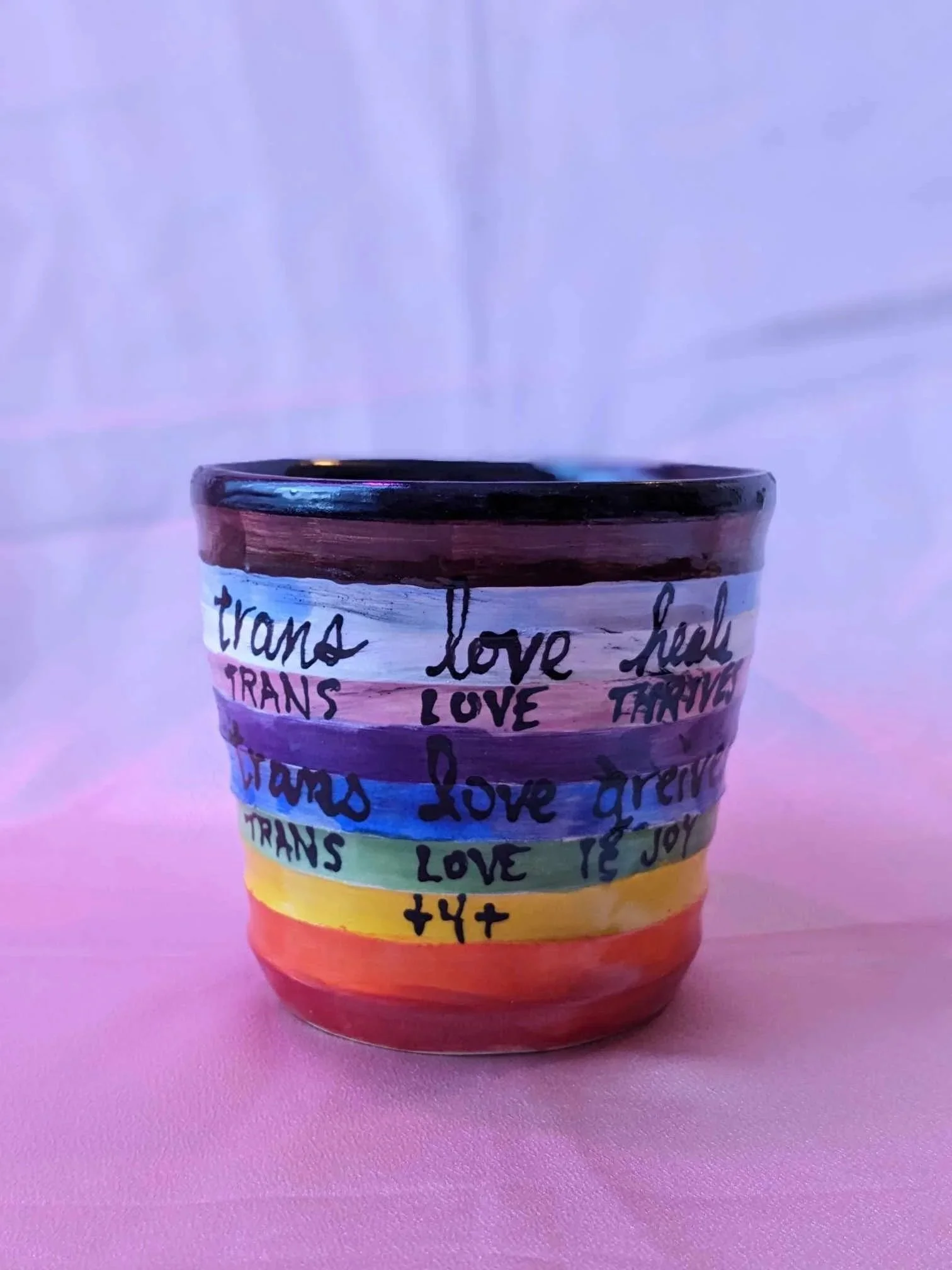 black and white photo of a cylinder shaped ceramic pot. the pot has a long human torso with arms stretched upwards 