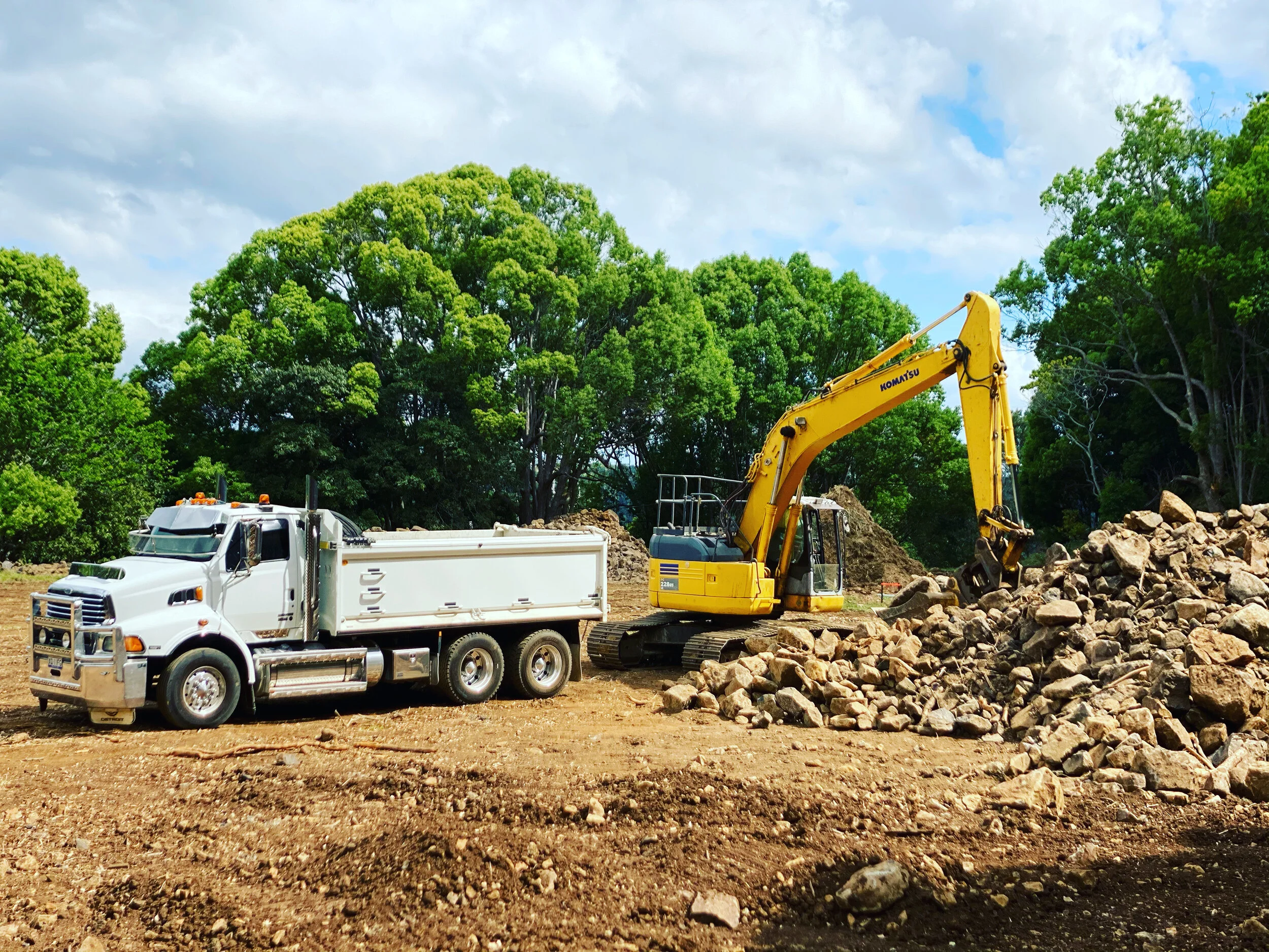 An excavator efficiently loads rock onto a tipper truck, showcasing Garbett's Excavations' expertise in rural projects. Our team's meticulous approach ensures seamless material handling, vital for advancing infrastructure development in rural areas. 