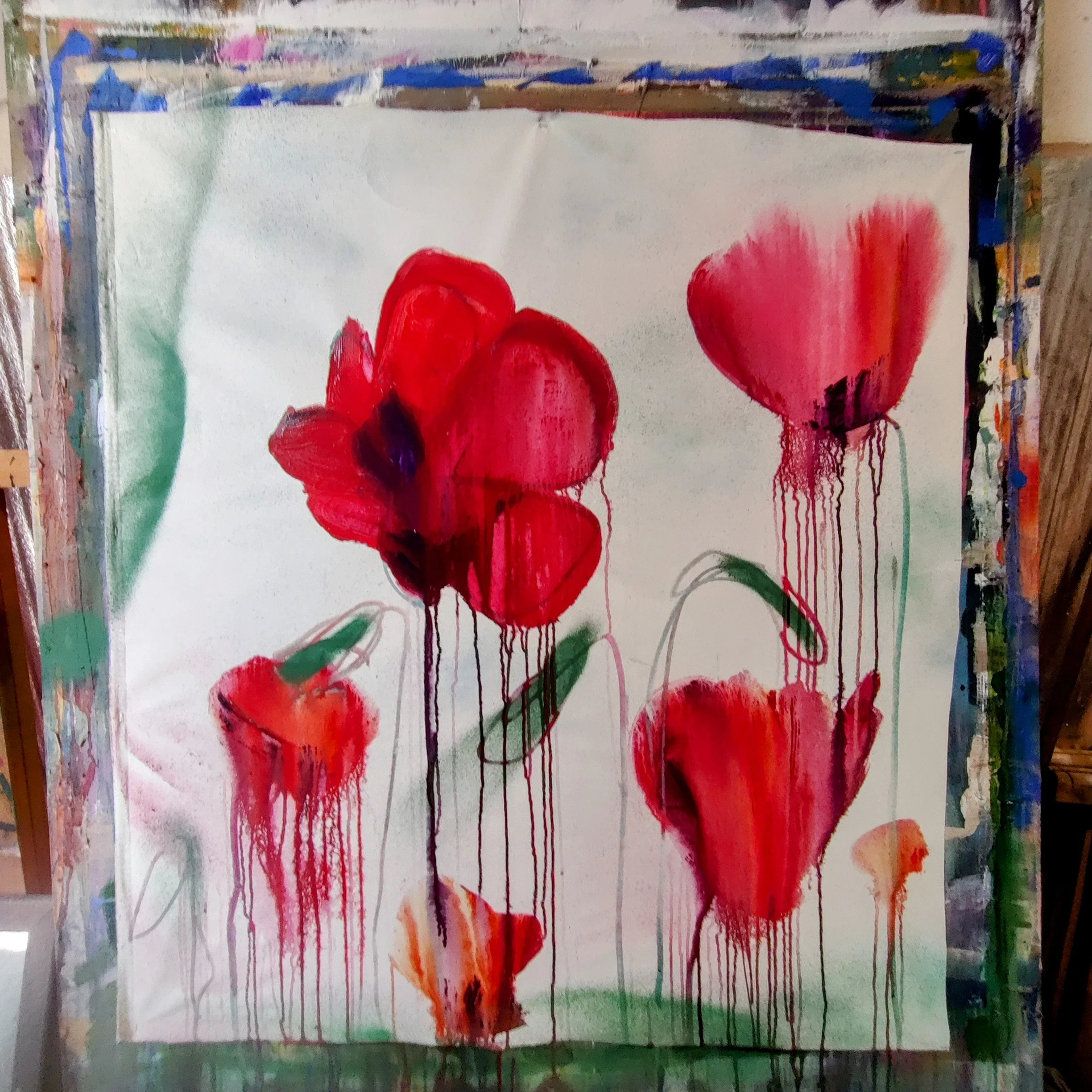 Abstract watercolor painting of red flowers with green stems on a white background, with drips of paint running down.