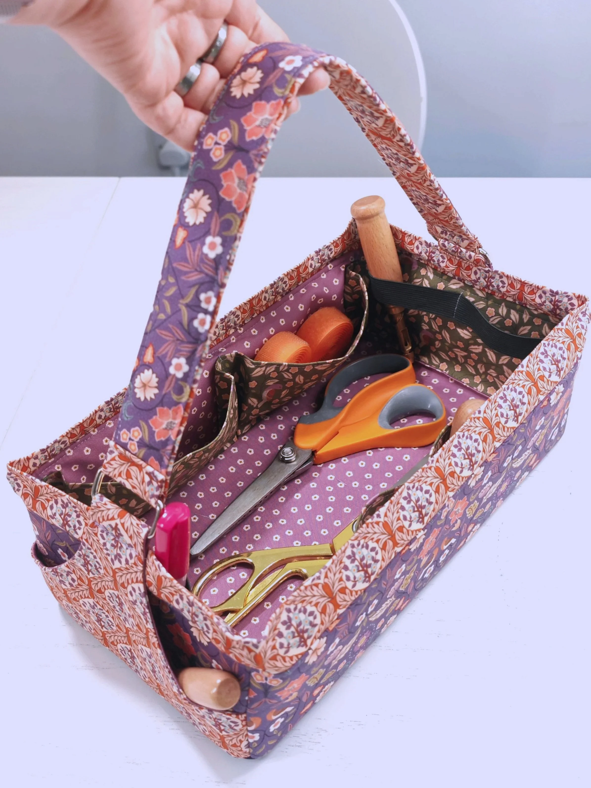 Fabric tool basket with strap, interior pleated pockets, elastic loops, and exterior pockets.