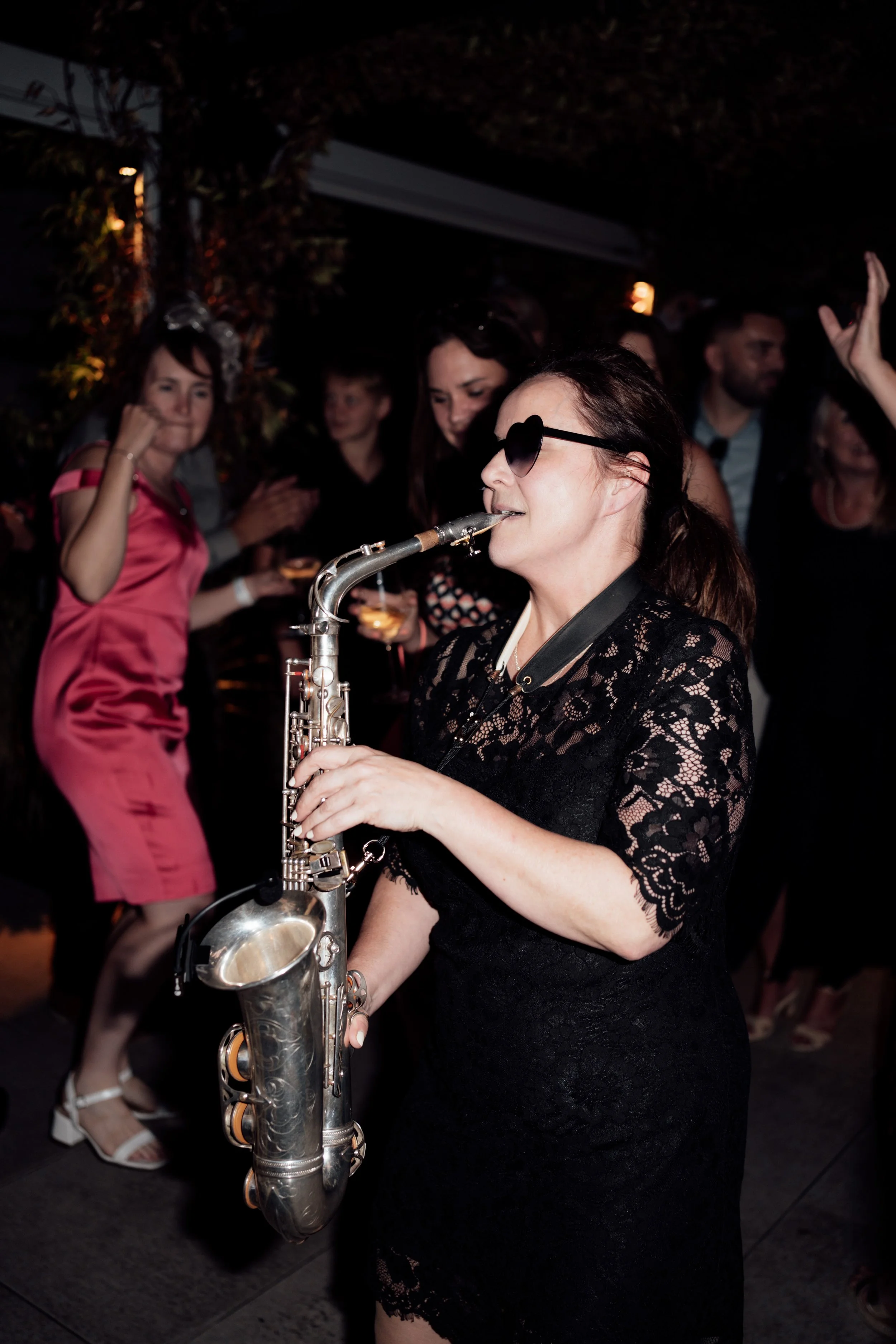 Wedding saxophonist performing live among guests on the dance floor