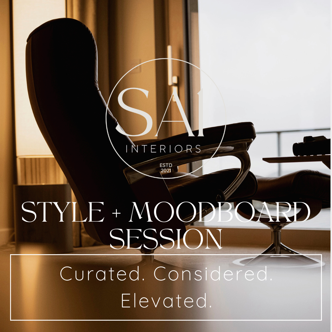 A woman with blonde hair wearing a striped shirt is sitting at a desk looking at a color palette swatch book.