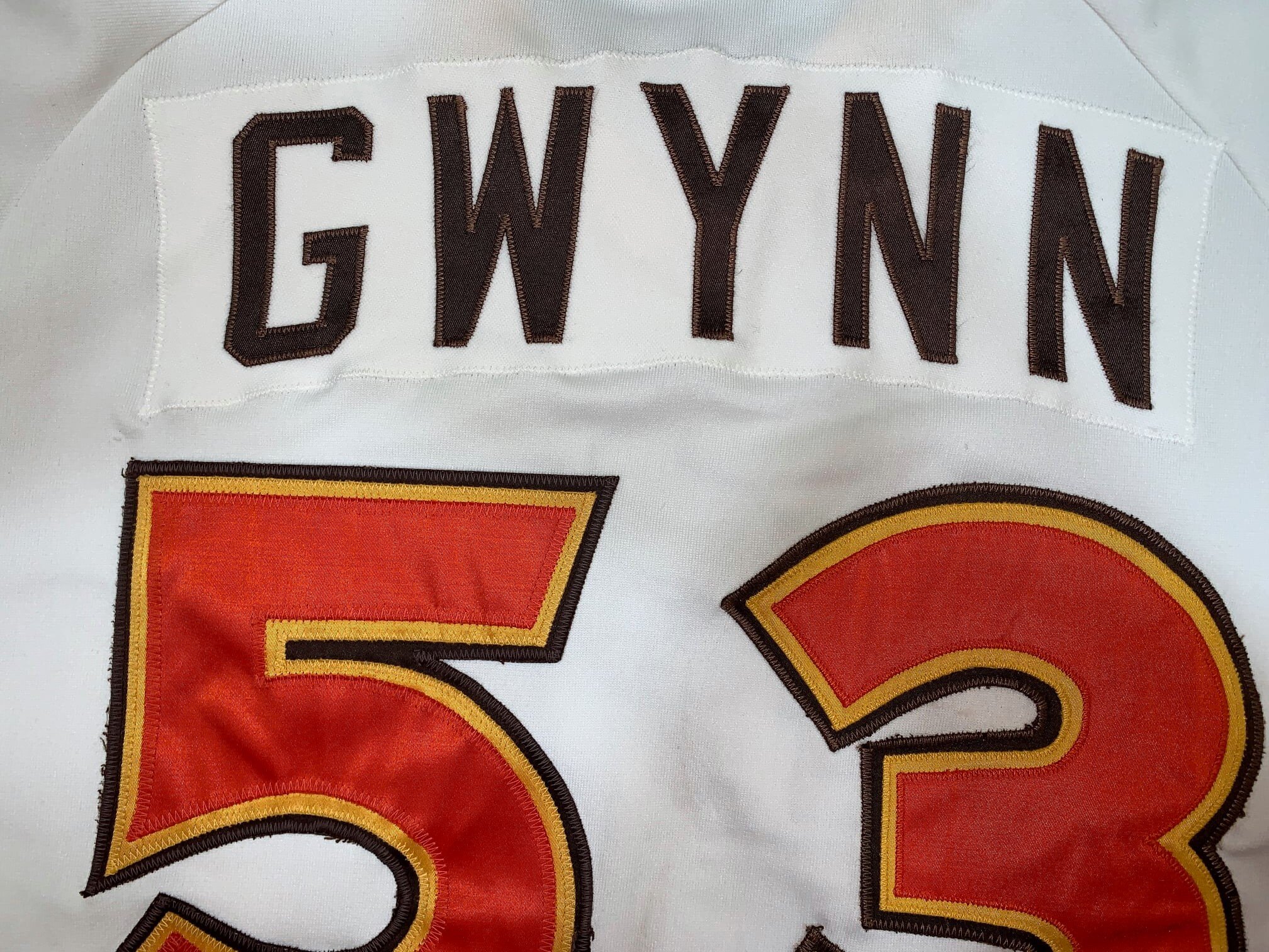 The nameplate was recreated using fabric harvested from another perfectly matching, equally aged and laundry-faded period warp knit jersey. The player letter spacing was replicated using three data points: 1.) Visual evidence of where the name "Gwynn