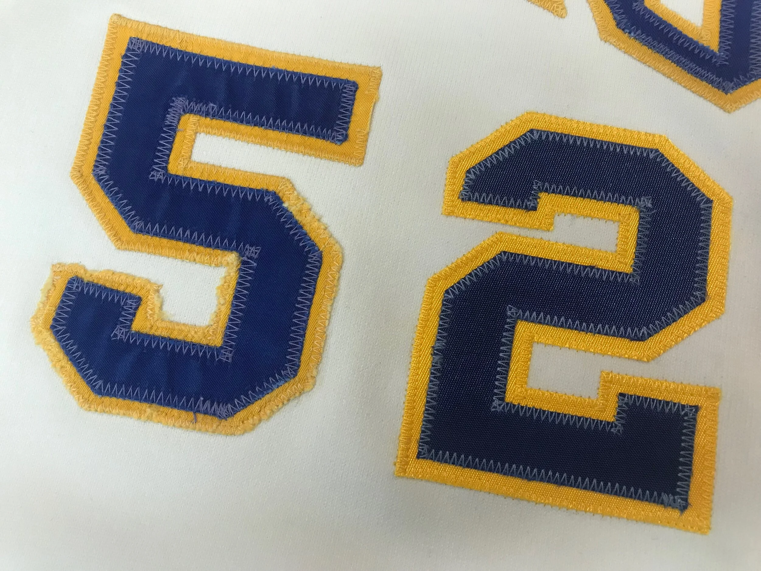 Here, the old "5" next to the replacement "2" sewn with the intentionally off-color thread to mimic years of washing. The yellow fabric is slightly brighter than the old, due partly to its shininess and the fact that it hasn't been washed 300 times.