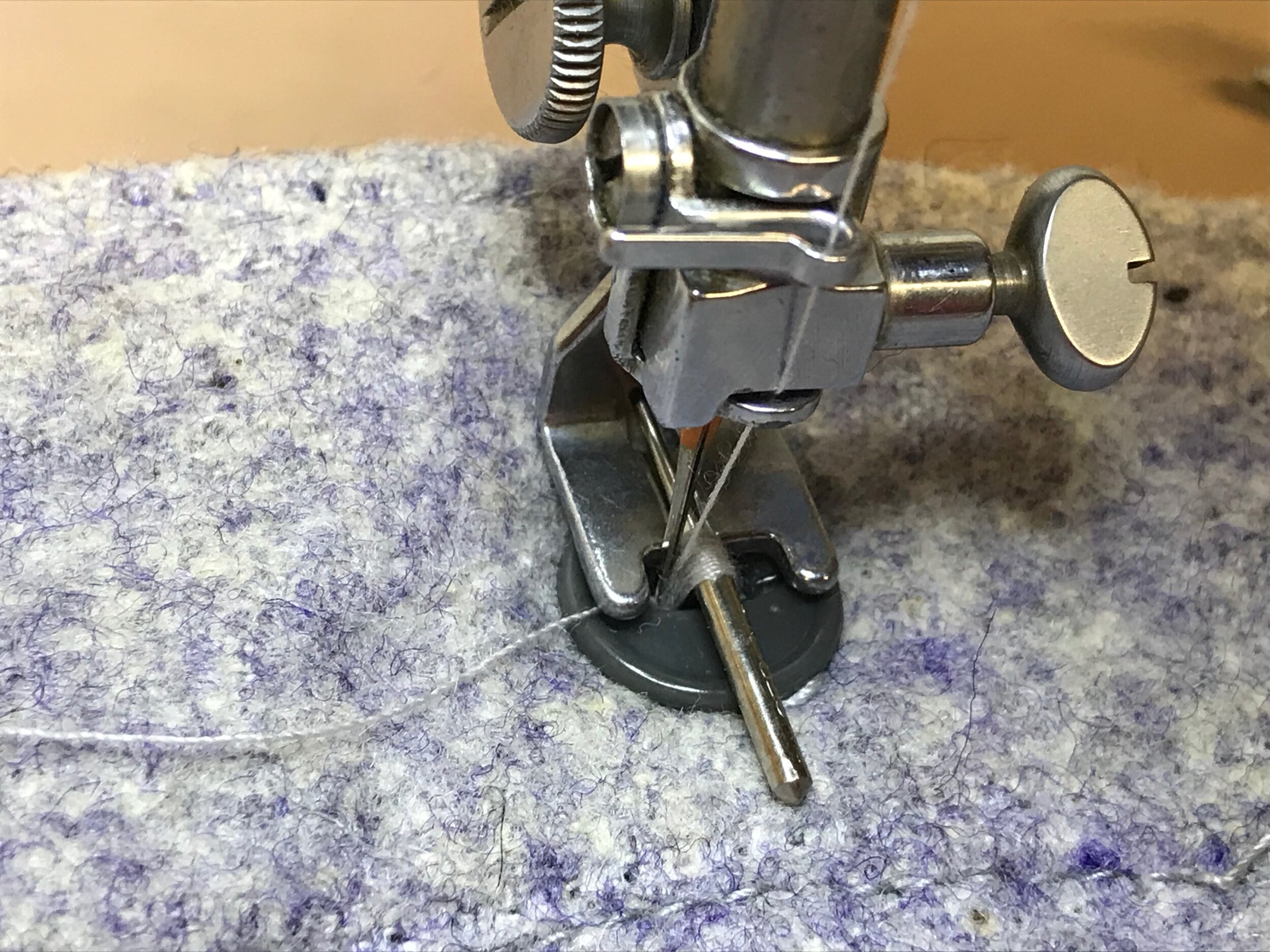 The sewing machine has a special foot to sew buttons. The bar in the center is an extra  needle inserted as a spacer. If I omitted the needle/spacer when sewing, the button would be sewn so tightly to the shirt that you'd never be able to get the but