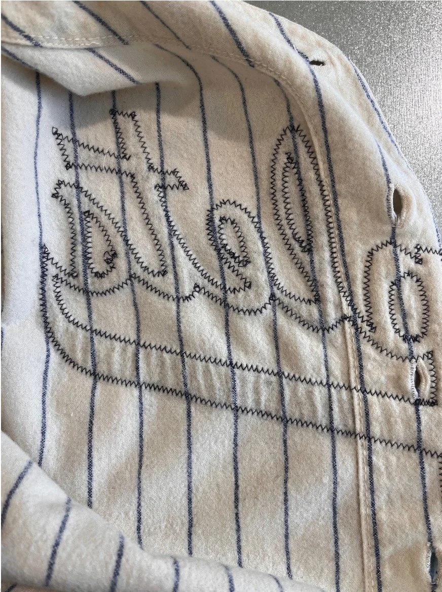 Putting it on the light table, we can see a few very faint marks where the Yankees New York crest had been on the front (more on that in a moment) but I also notice the signature puckering underneath the Triplets logo. That tells me it was washed man