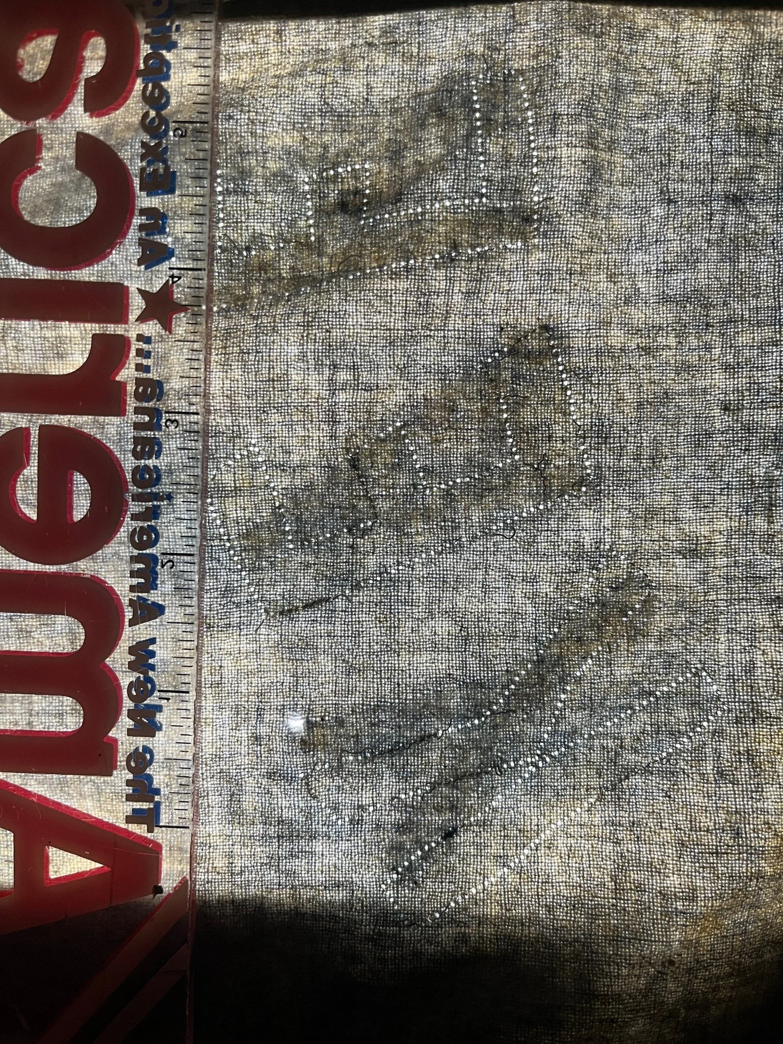 To make exact patterns of the original lettering, I have a specific process I follow. First I put the garment on the light table, and lay a translucent ruler on top of it. Then using my camera I photograph the area at different degrees of exposure, k