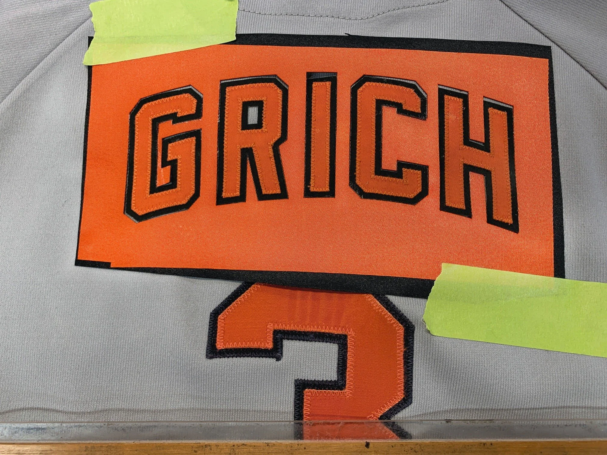 I lay out all lettering prior to cutting it. That way it is always applied perfectly arched and spaced. Notice the reflectiveness of the surrounding material... because it is less reflective, it appears lighter than the number below it, or the name l