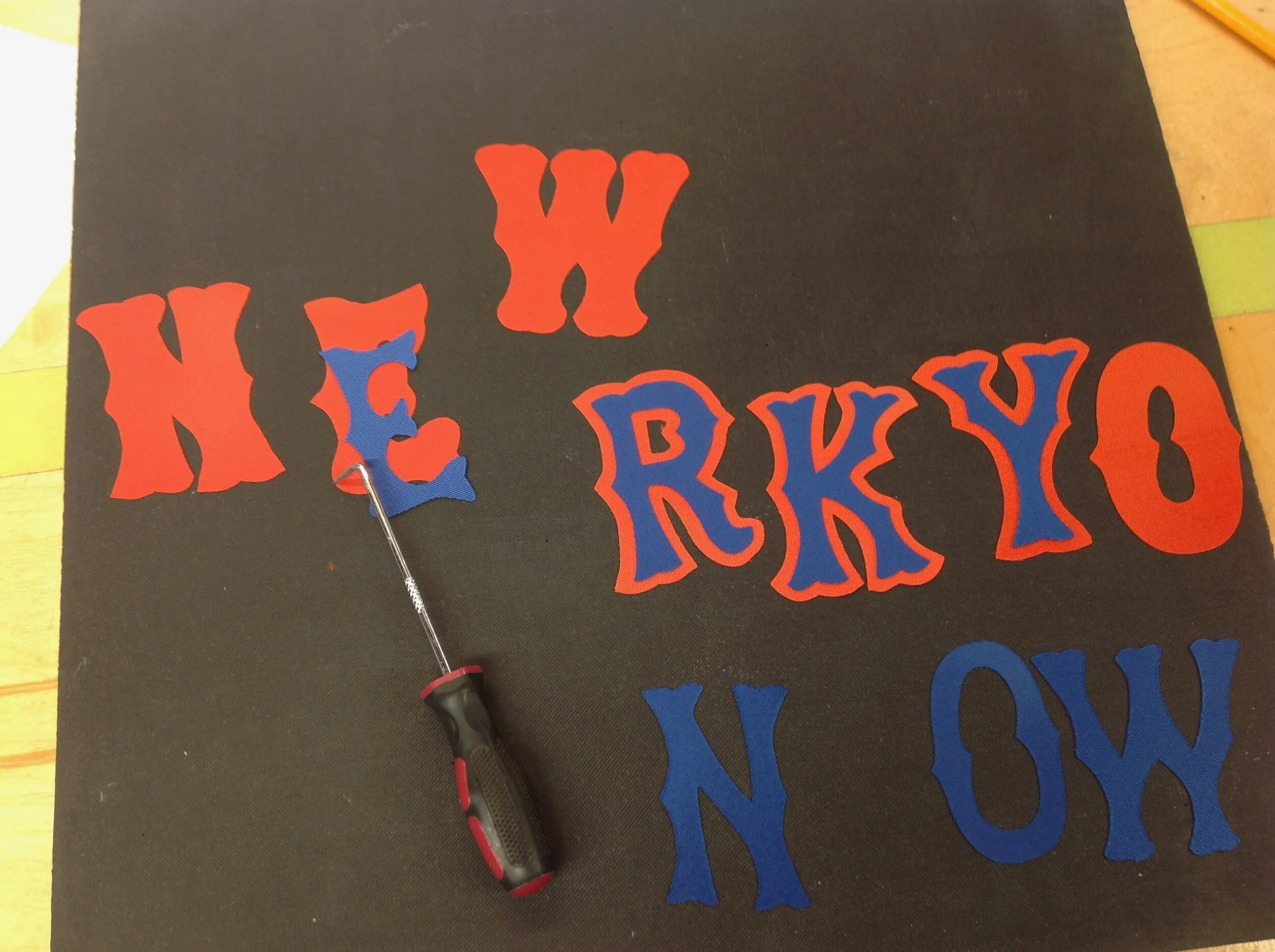 Using the computer-driven cutter, we cut the letters one color at a time, align by hand and then heat press them together.