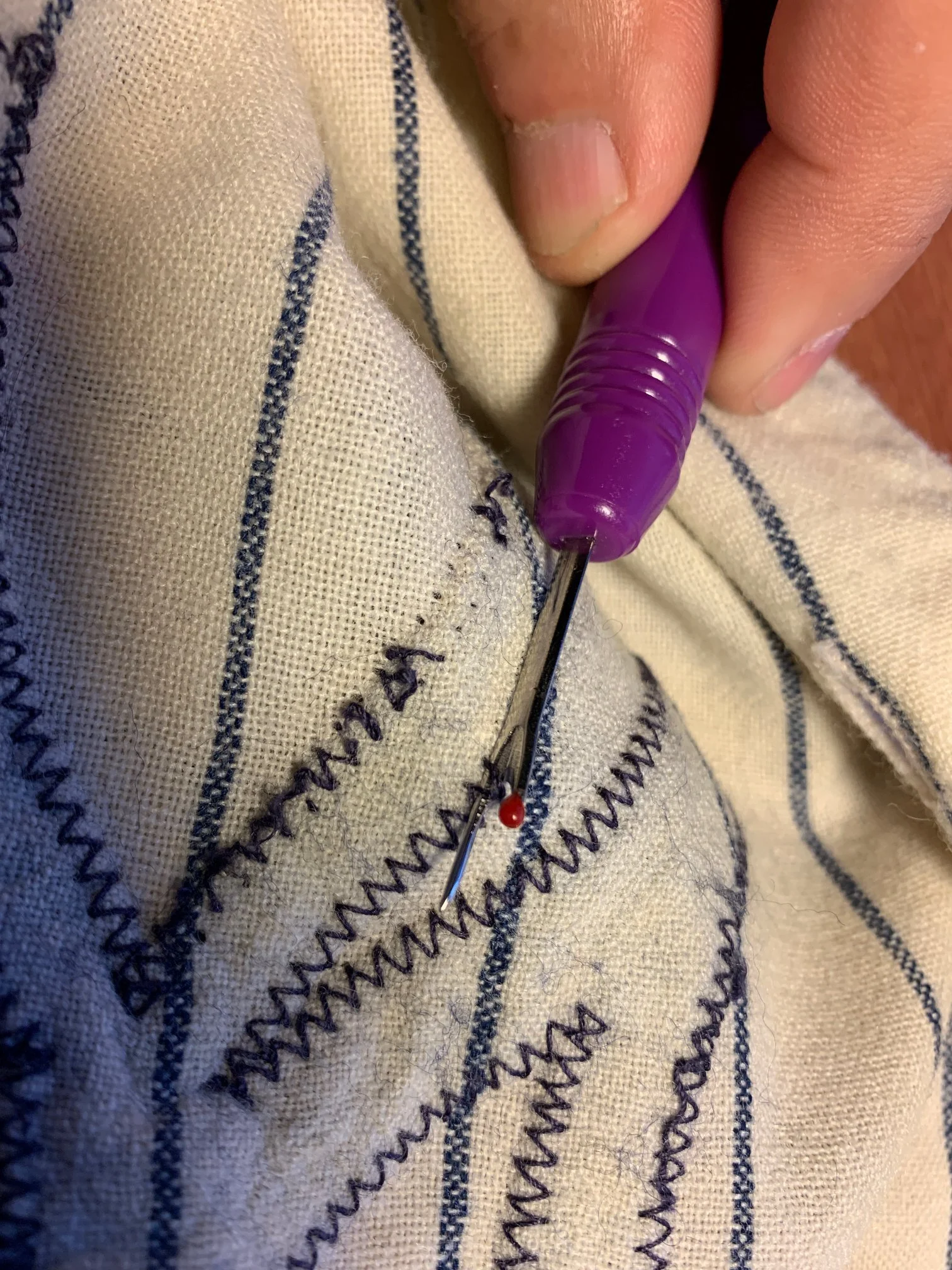 I *very* carefully removed the stitching holding the replacement NY on the front. Luckily, it was not glued on and came off without a fight. But unfortunately, its residence had stained the flannel fabric below after decades of contact with it. Havin