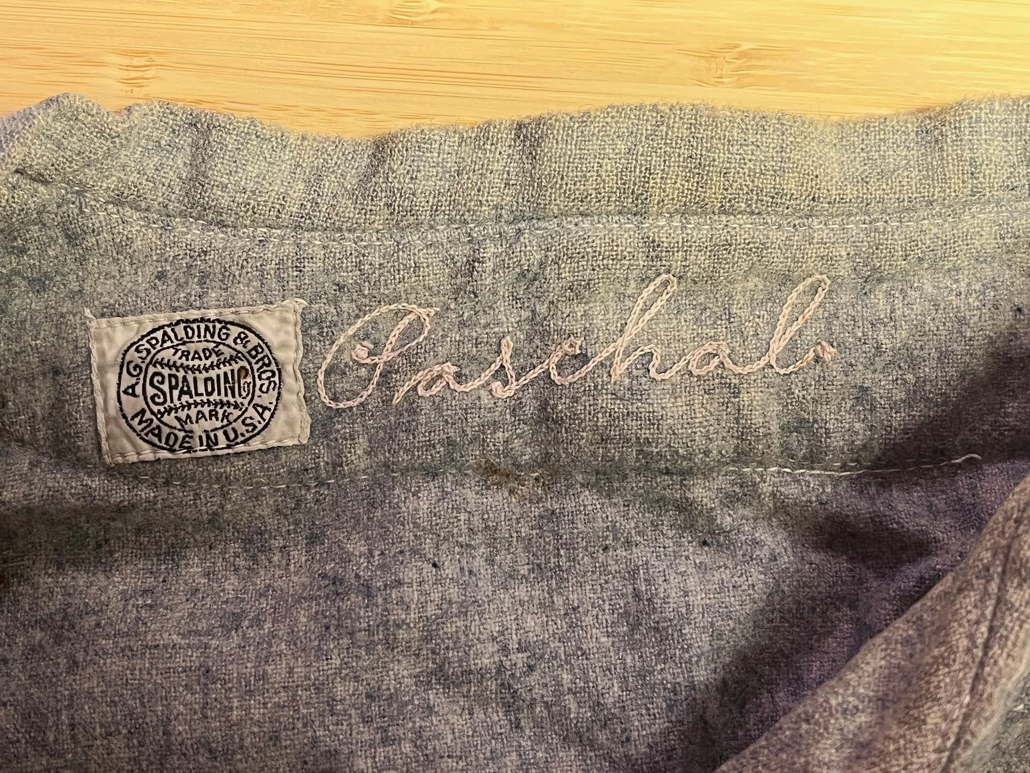 Spalding-made, It is clear that both of these jerseys had seen a lot of use, the material was worn thin in spots and several repairs were evident, as well as a few holes. But wait— there are names elegantly chain-stitched by hand in the collar: “Coll