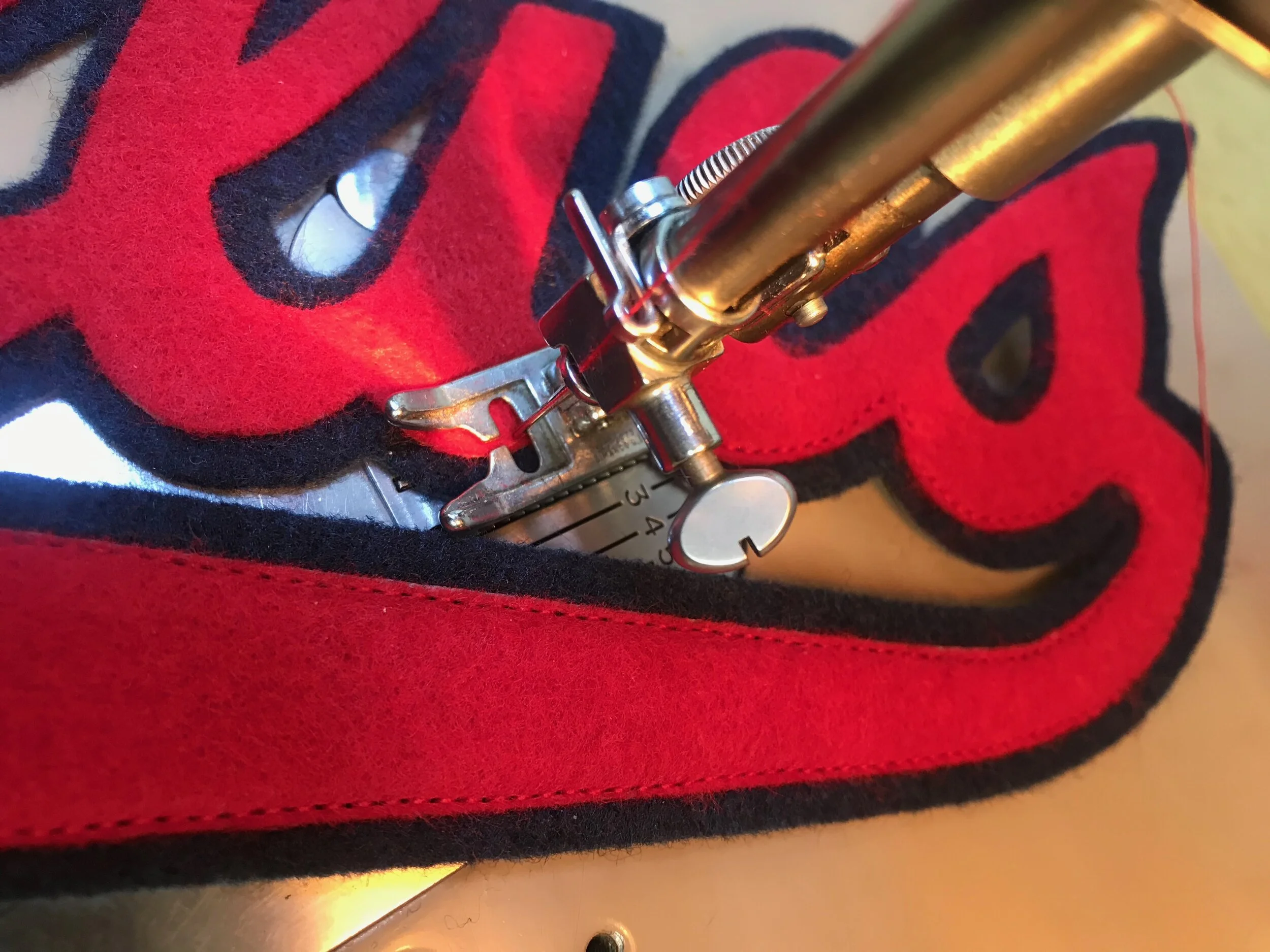 Next, I edge-sew the layers together. Felt lettering is typically straight stitched, like this. Twill has a woven edge that can unravel, so a zig zag stitch is used with twill.