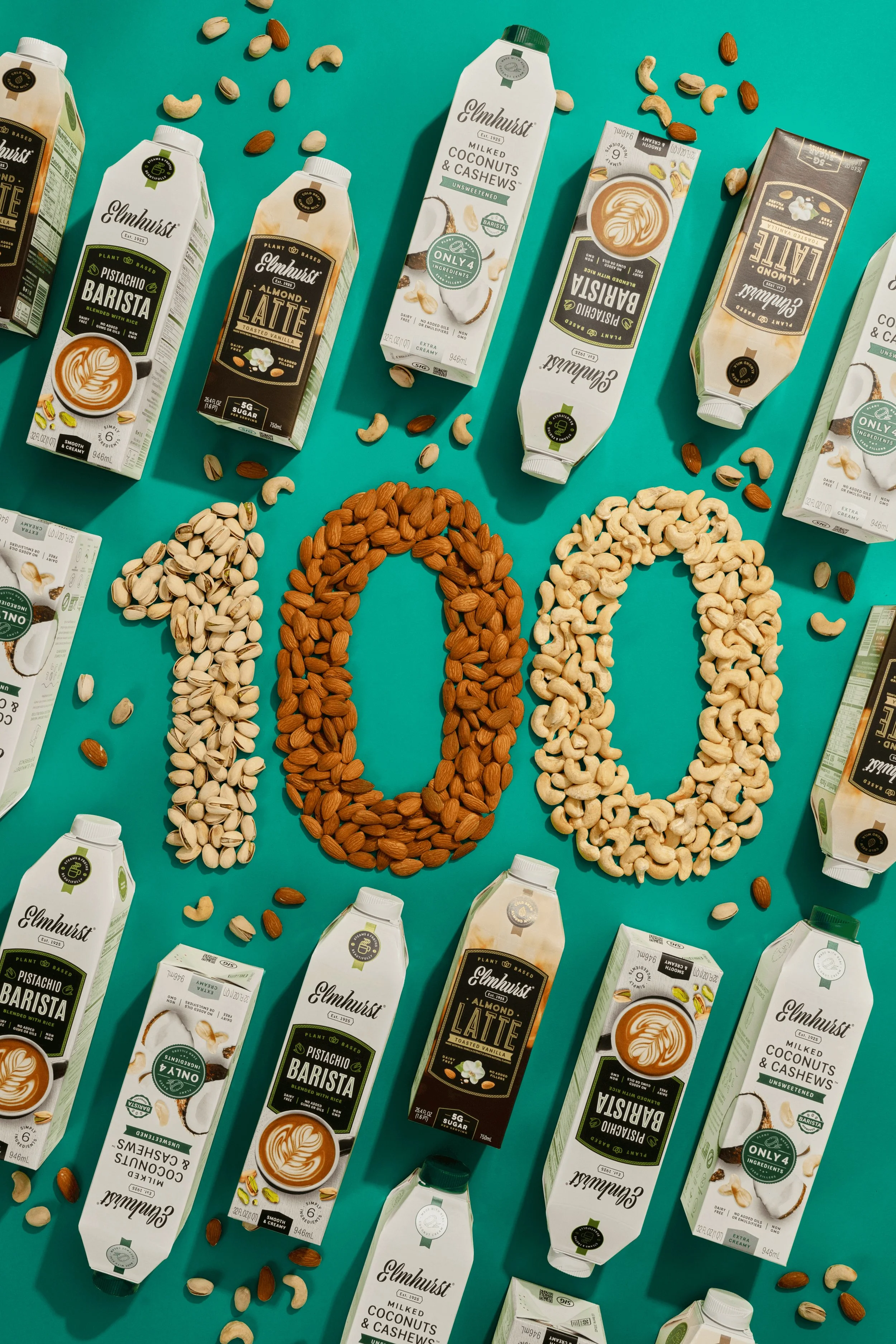 Various plant-based milk cartons on a teal background, with scattered nuts arranged to spell the word 'milk'.