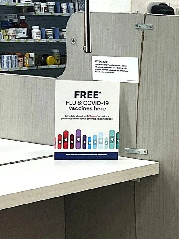 "Free* Flu & COVID-19 vaccines here" Printed Flyer in Acrylic Sign Holder, Vaccination Area at CVS Pharmacy in Target, Shoreview, MN - September 27th
