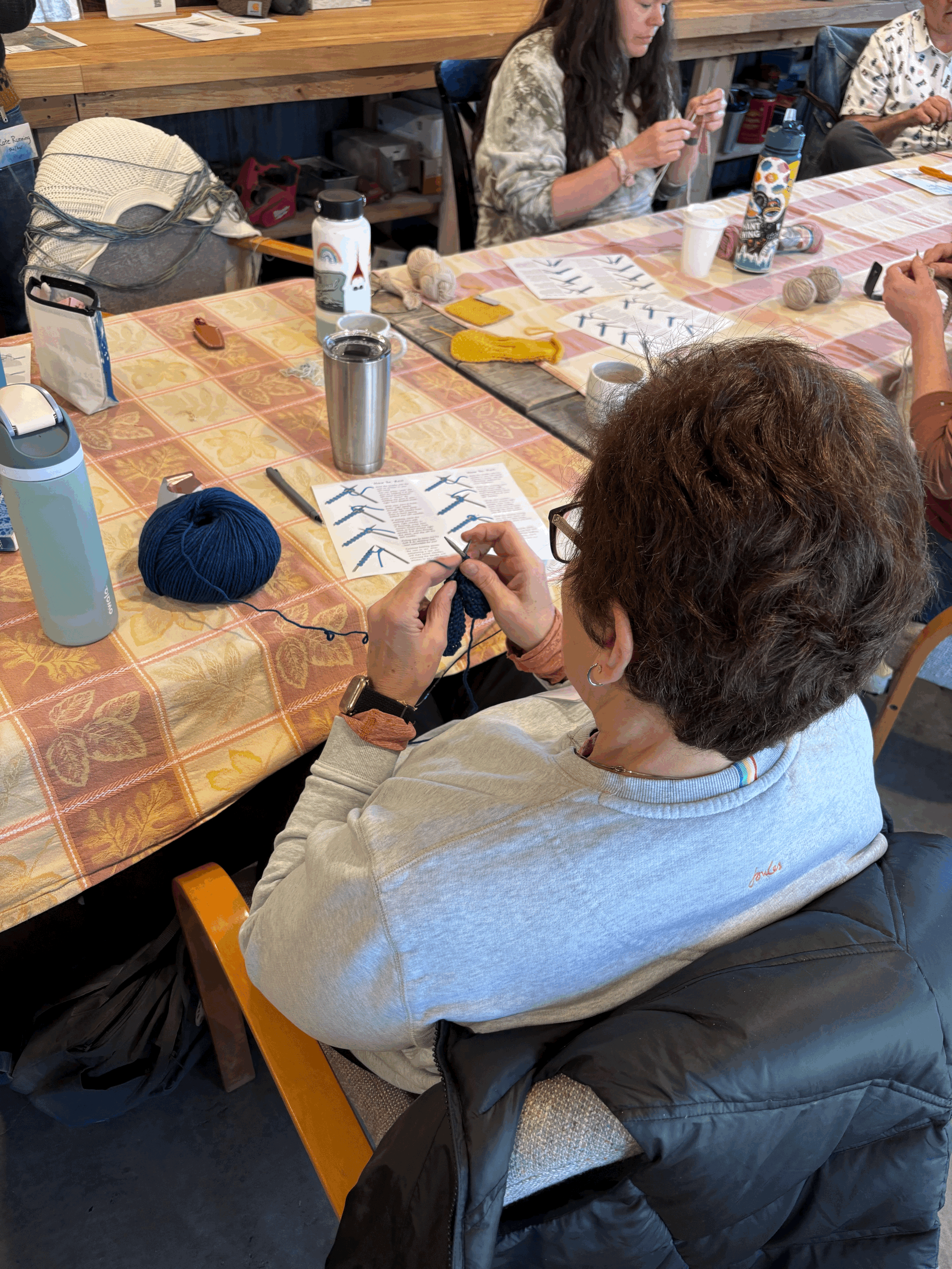 a group of people around a table knitting