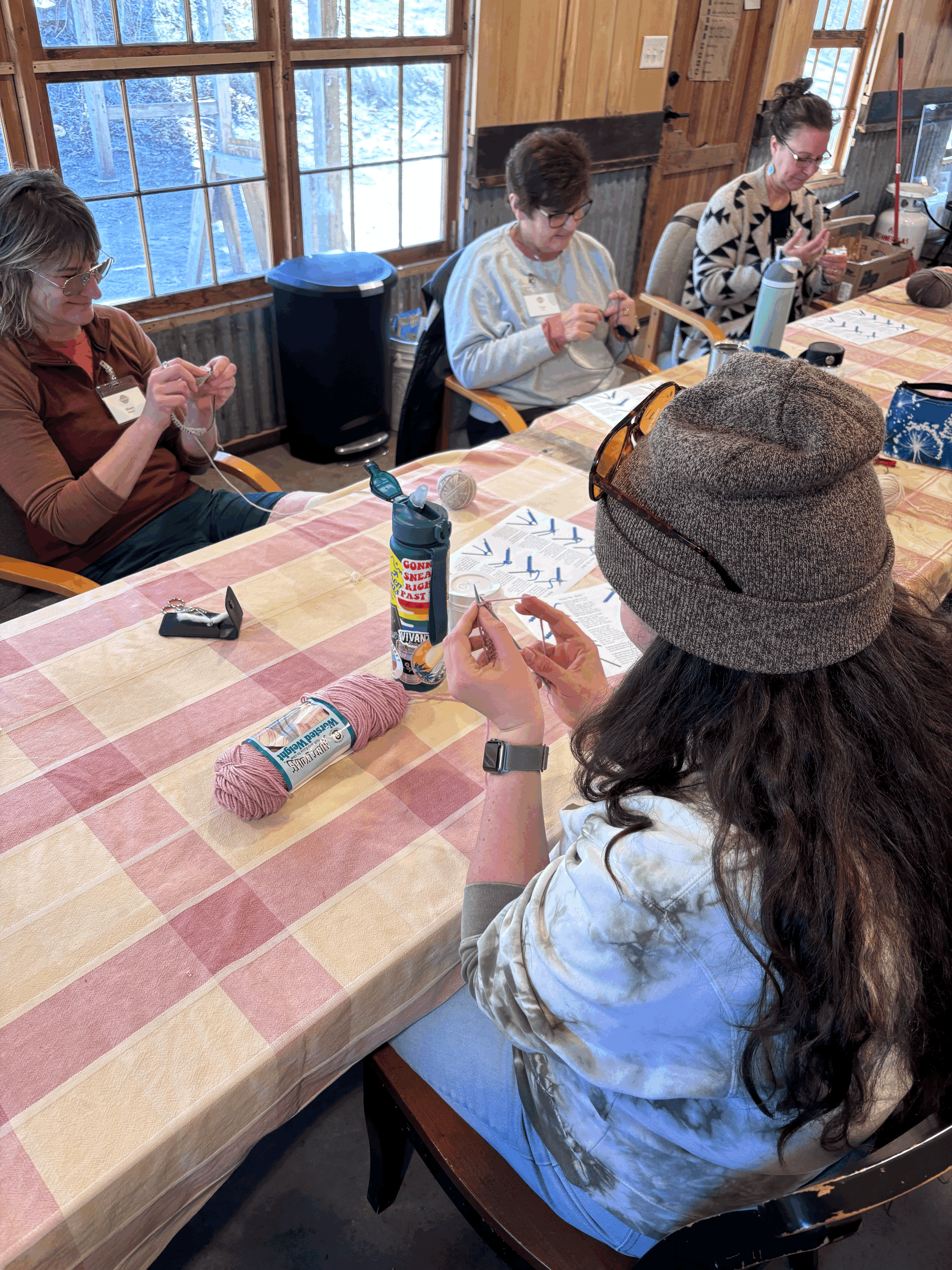 a group of people around a table knitting