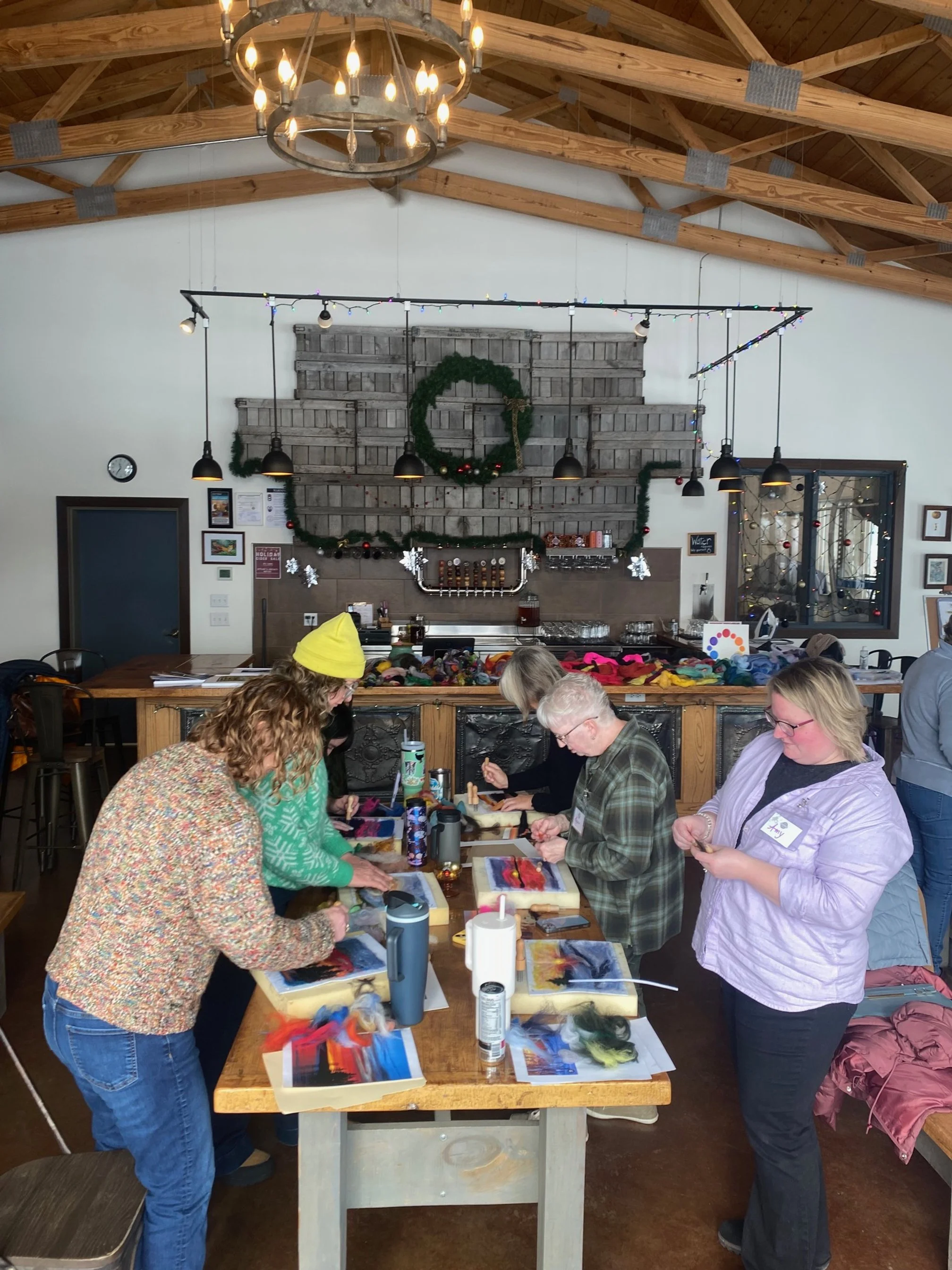 people sitting at tables working on needle felted landscape artworks