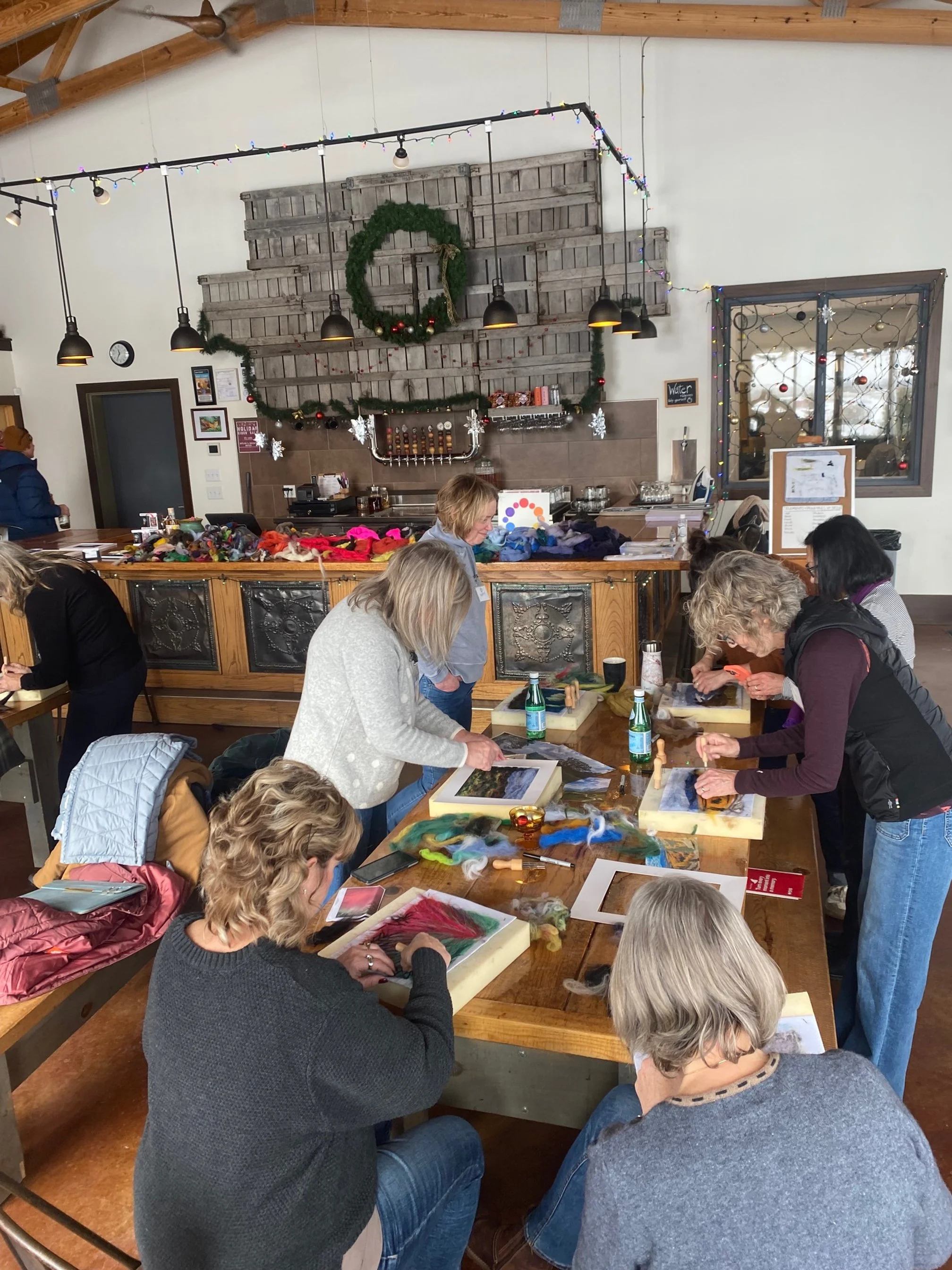 people sitting at tables working on their needle felted landscape artworks