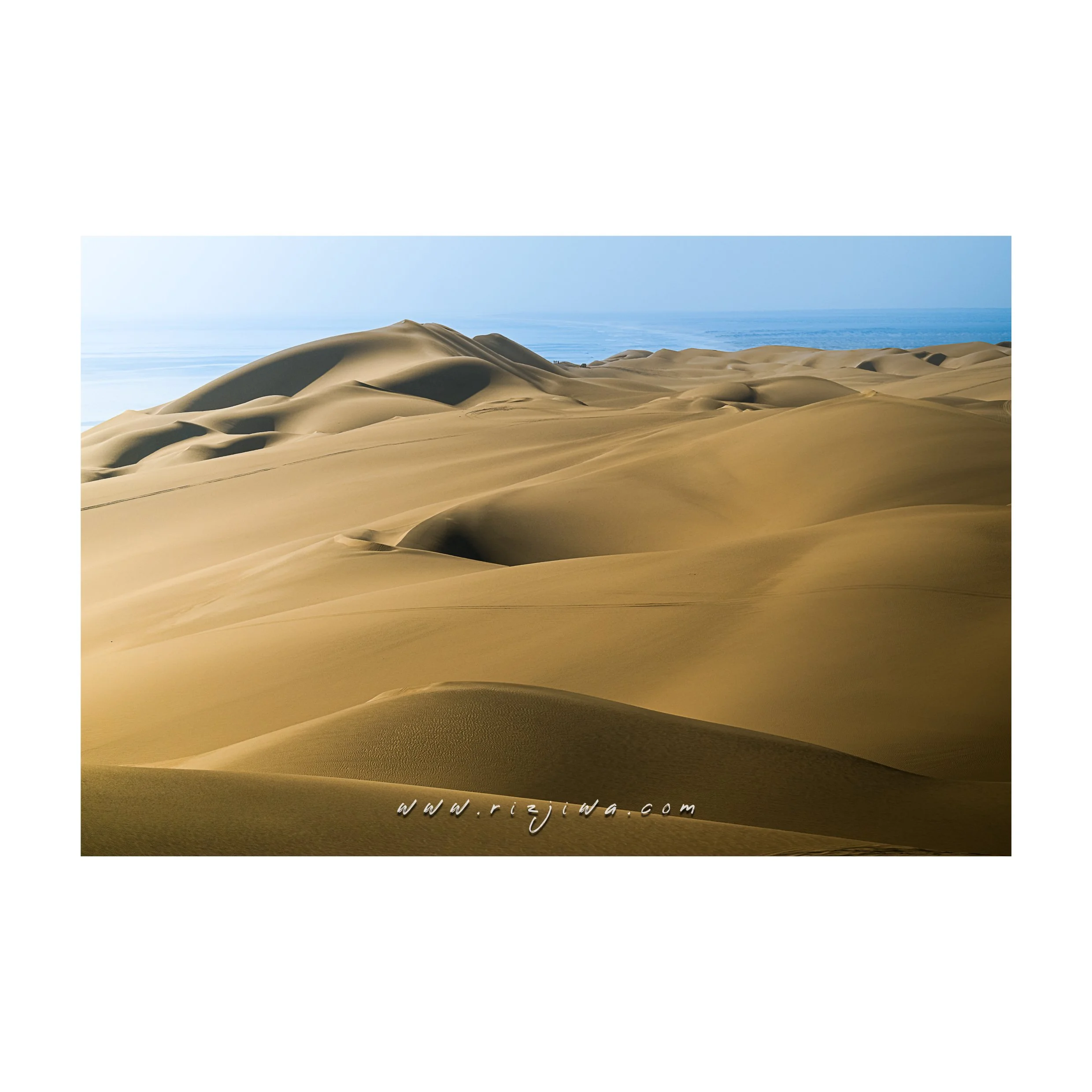 Desert landscape with sand dunes and a clear blue sky.
