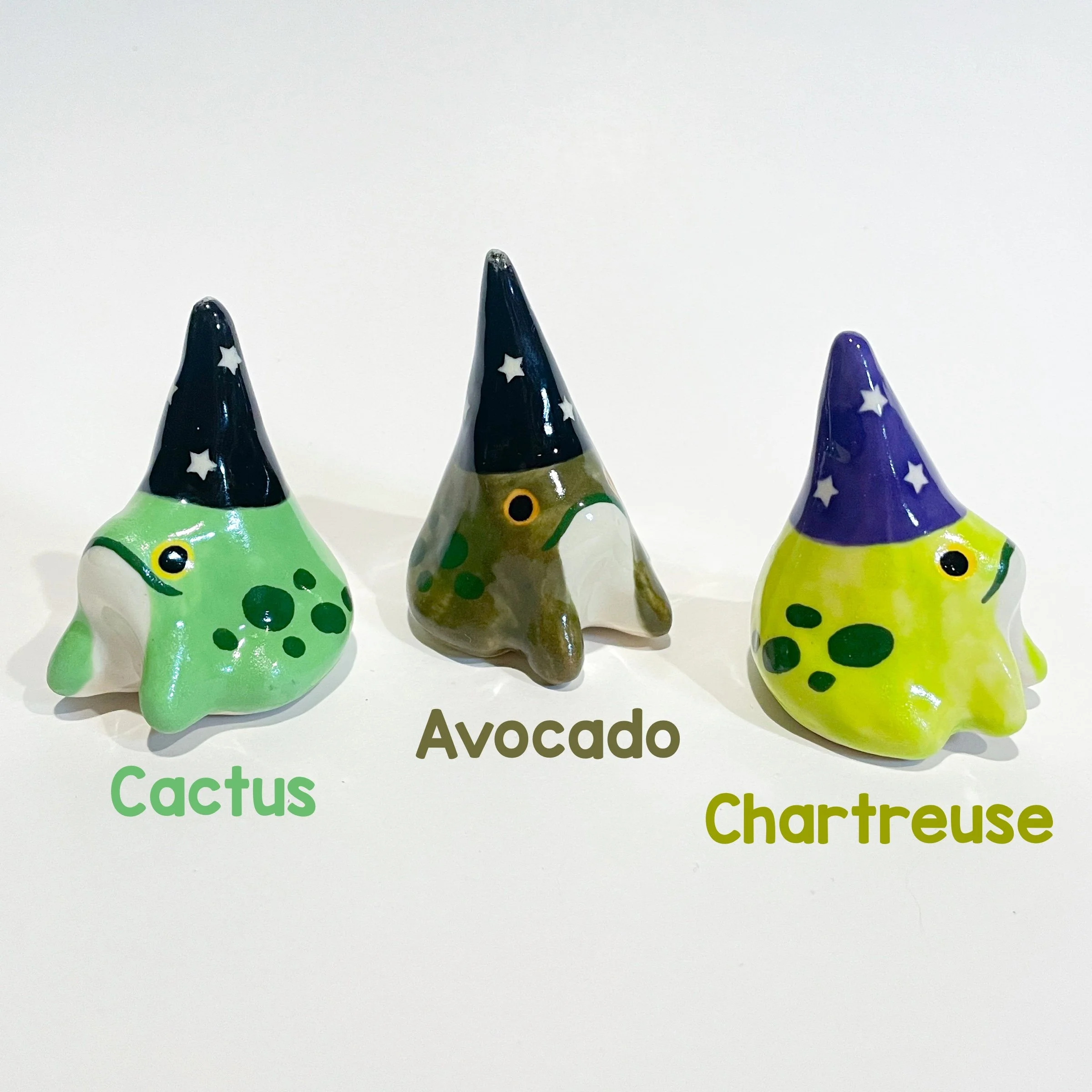 Three ceramic wizard frogs in varying colors