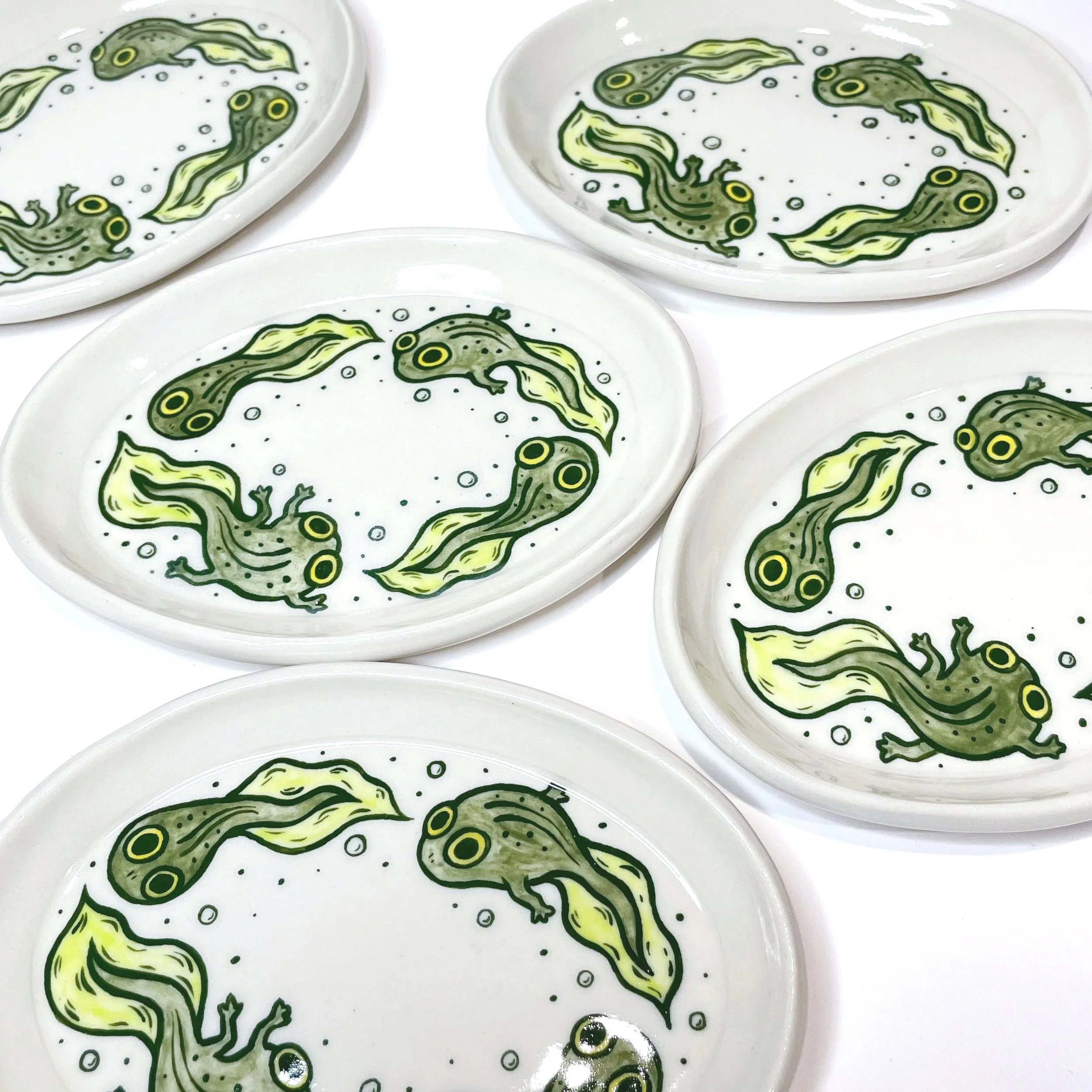 oval trinket dishes with four tadpoles illustrated on them.