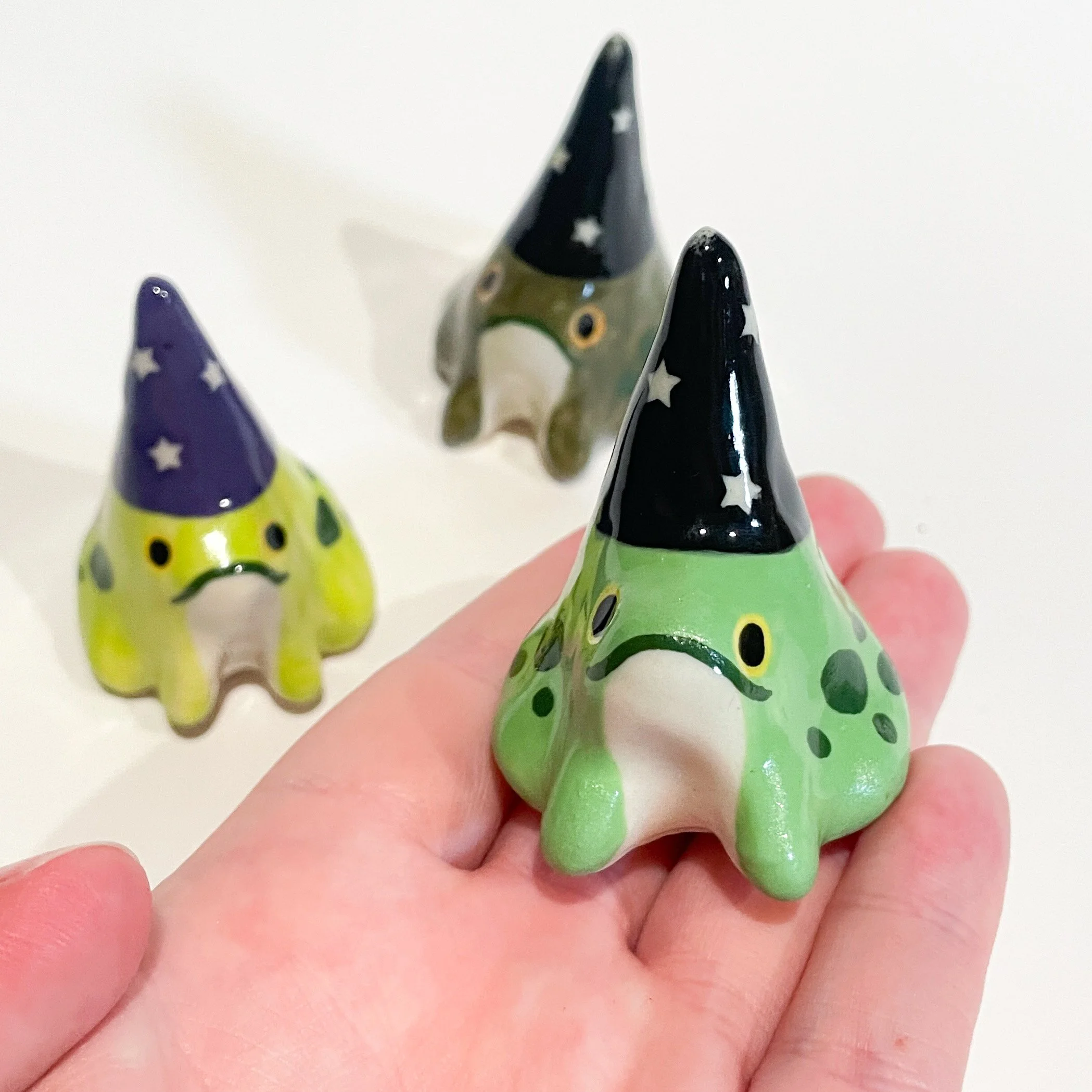 Three ceramic wizard frogs in varying colors
