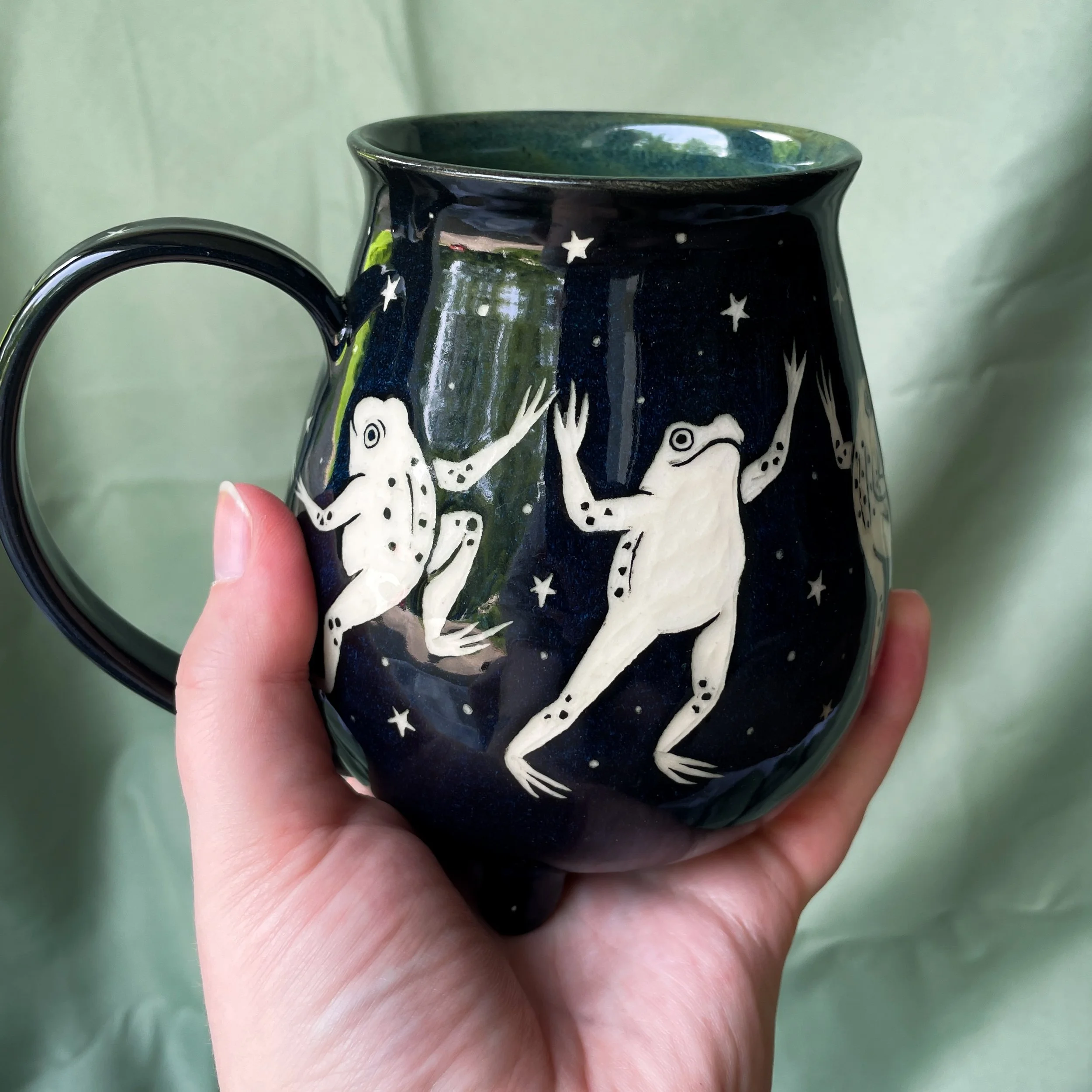 dancing frog cauldorn mug d being held.JPEG