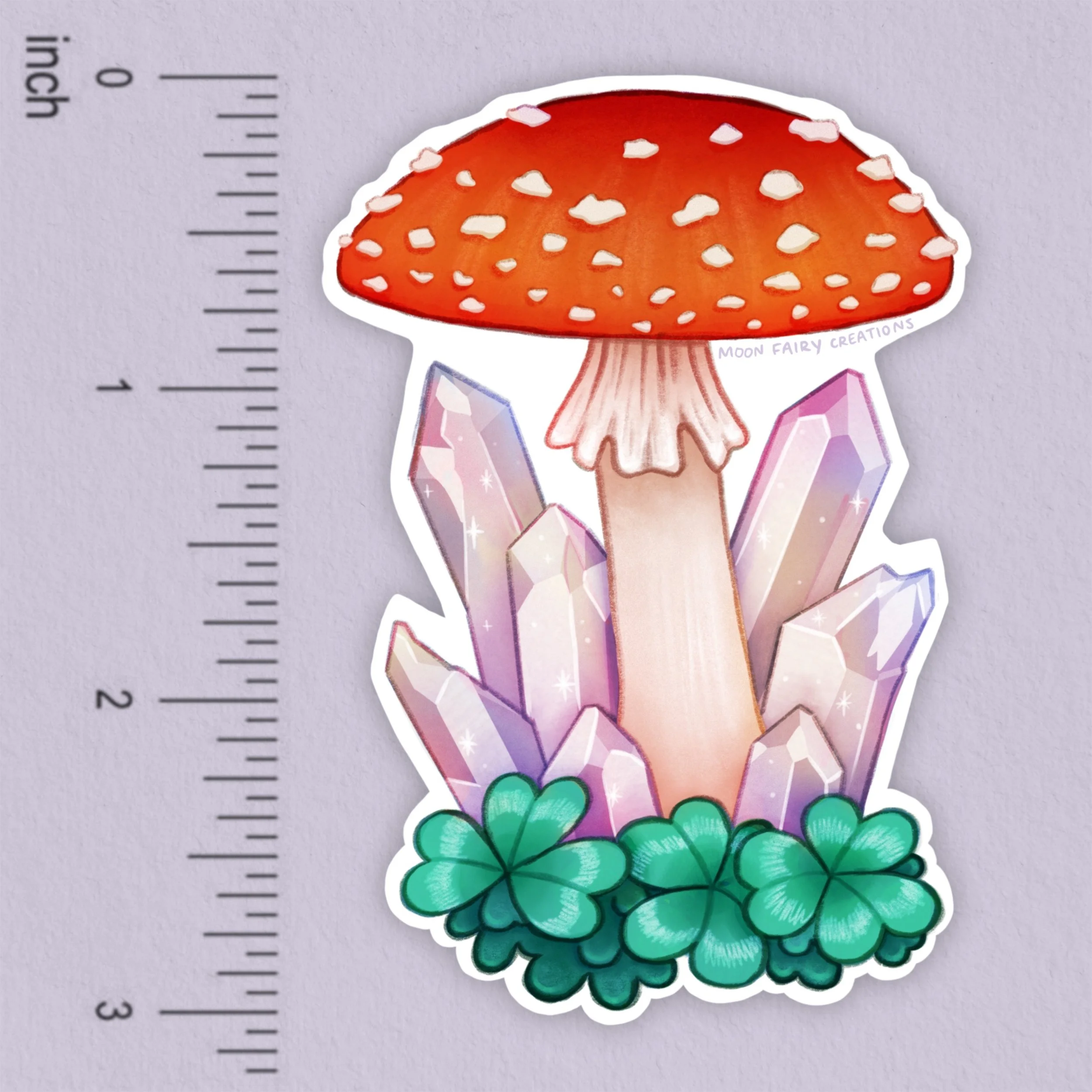 a sticker depicting a red amanita mushroom with crystals and clovers with a ruler showing it is 3 inches long