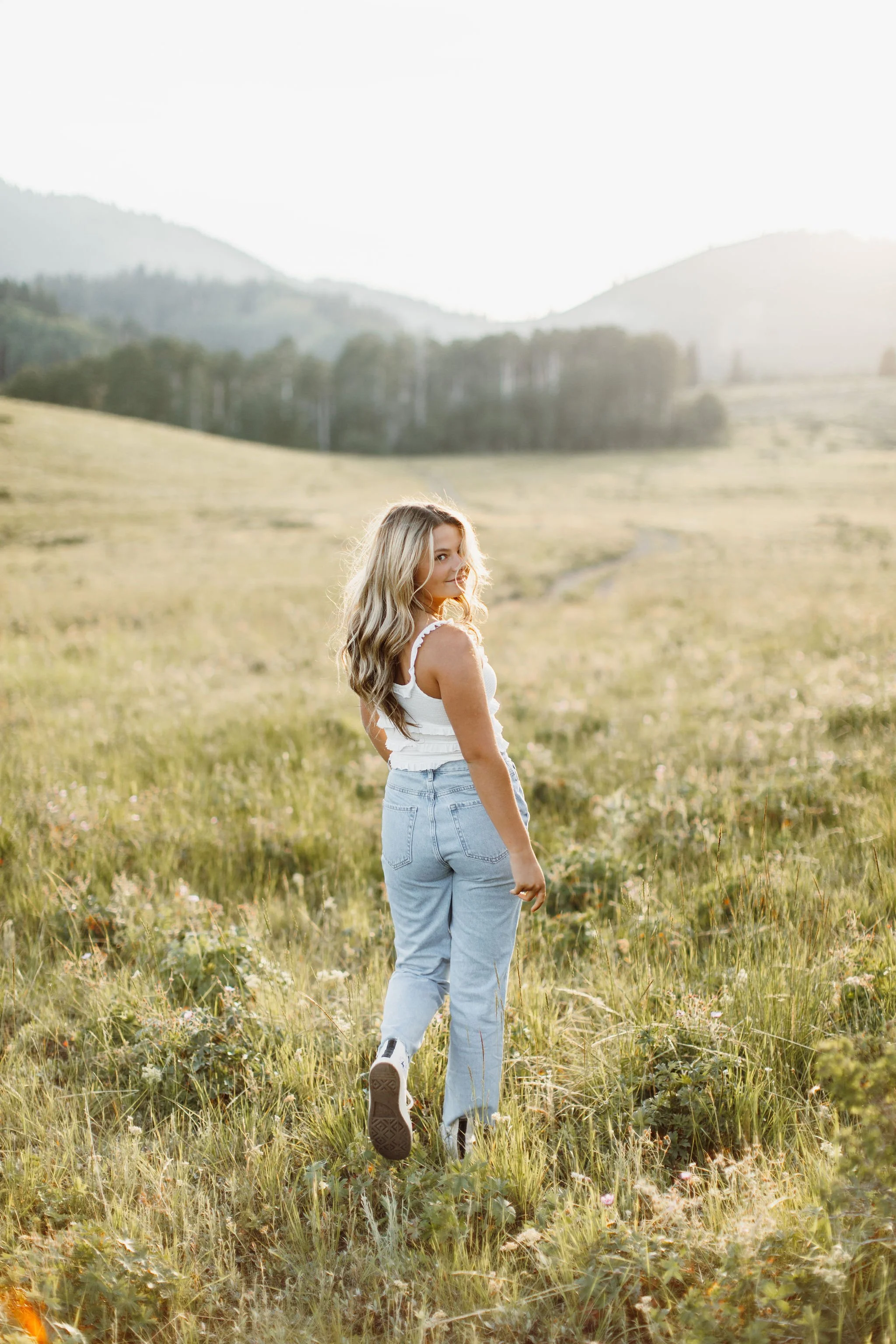 High school senior walking away from the camera, in a mountain valley at sunset. Park City Utah Senior Photos. Digital and 35mm film photography.