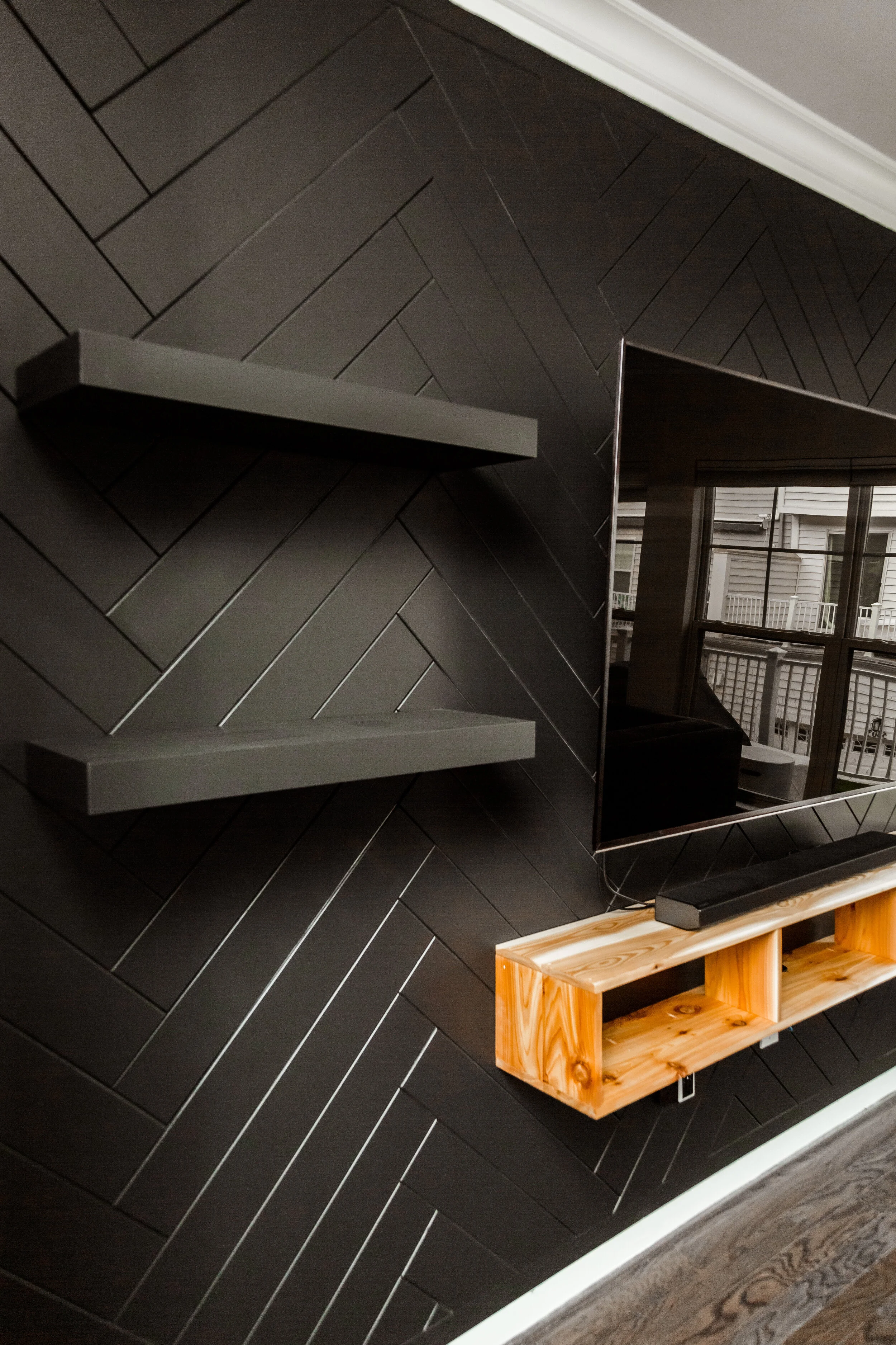 Herringbone wall with custom floating shelves and cedar entertainment console.
