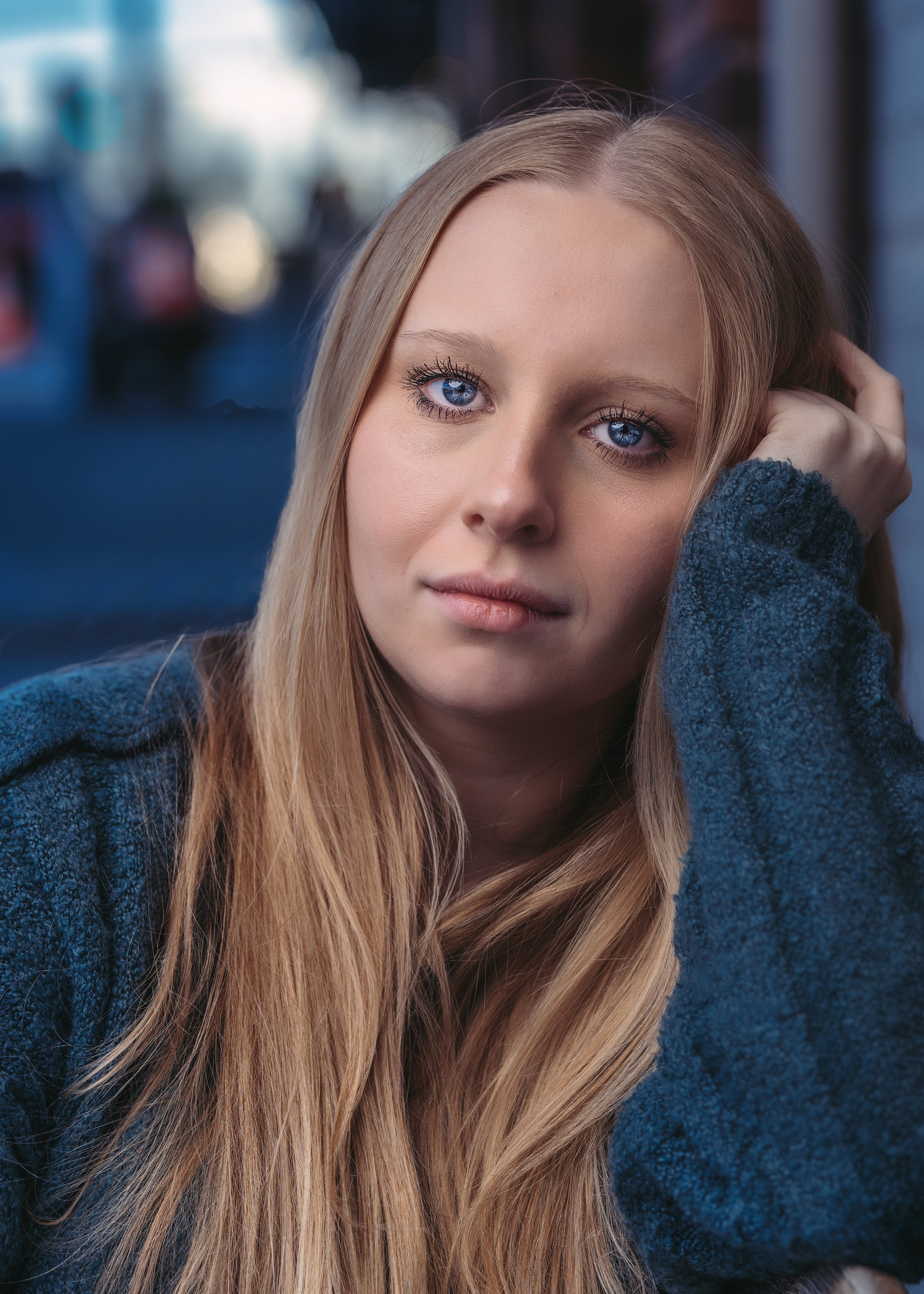 Woman with long blonde hair in a blue sweater looking at the camera.