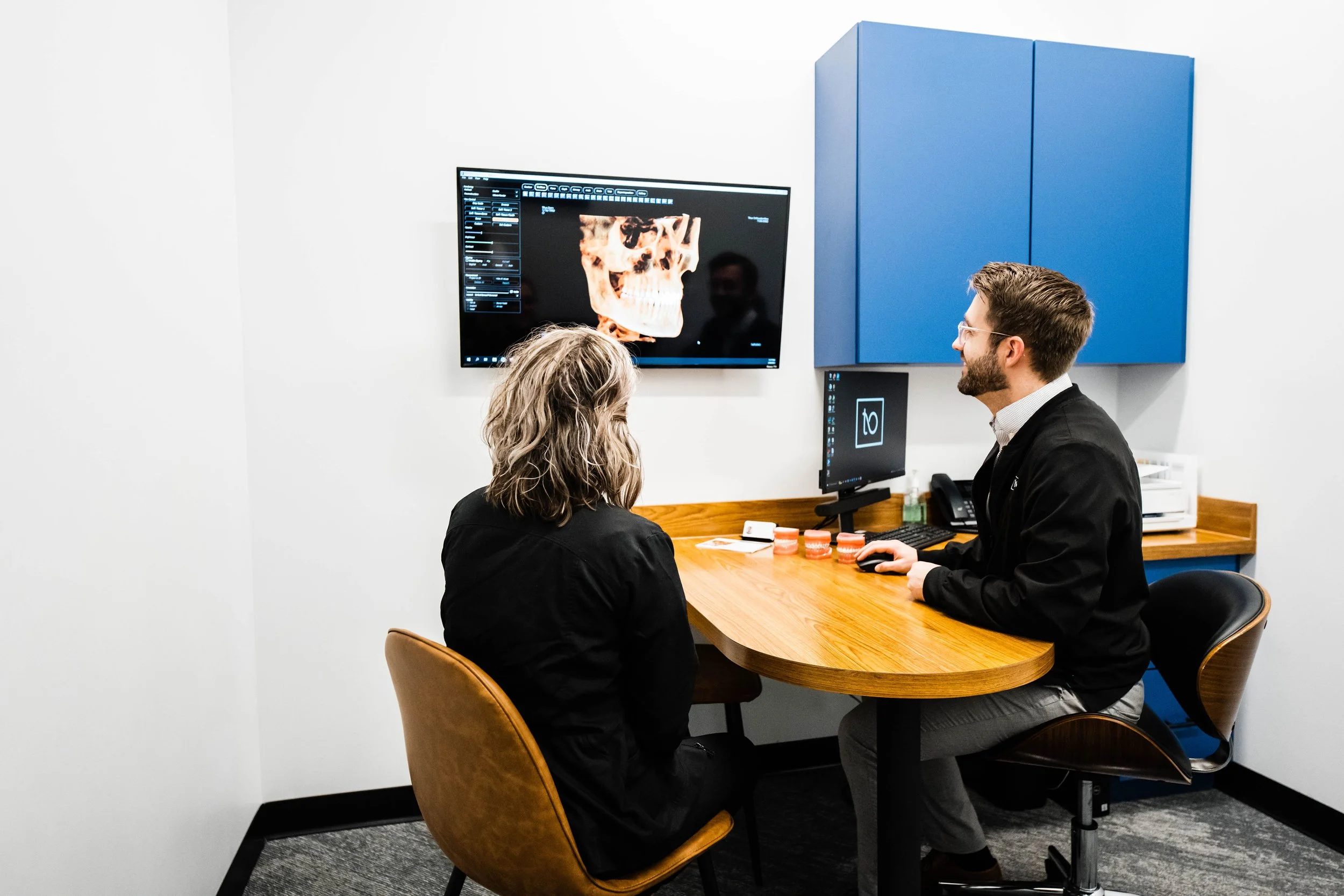 Patient seated at a desk speaking with a dental professional during a consultation - TMJ Treatment in Westfield, IN